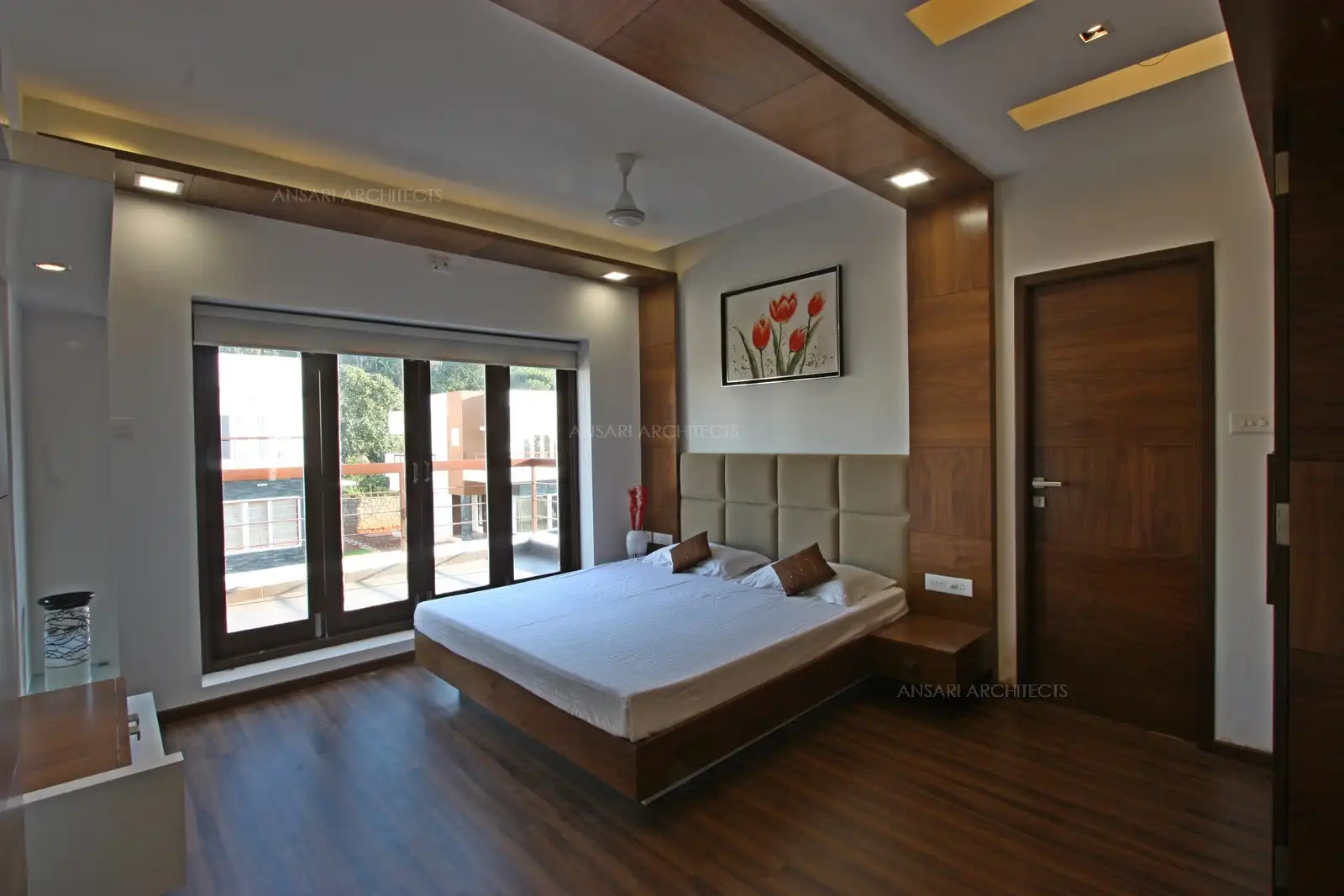 The room blends warm wooden finishes with floor-to-ceiling windows for a cozy yet airy feel.