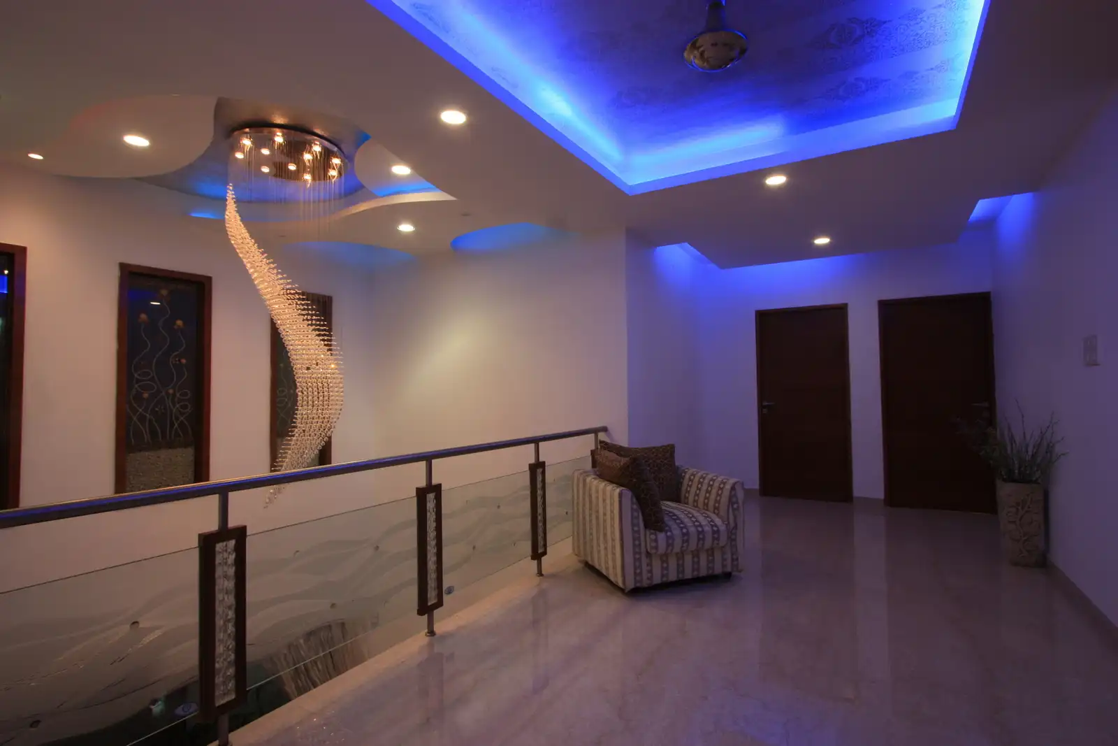 View of the double height ceiling as seen from first floor showing the chandlier and designer fixed glass at the second floor level.