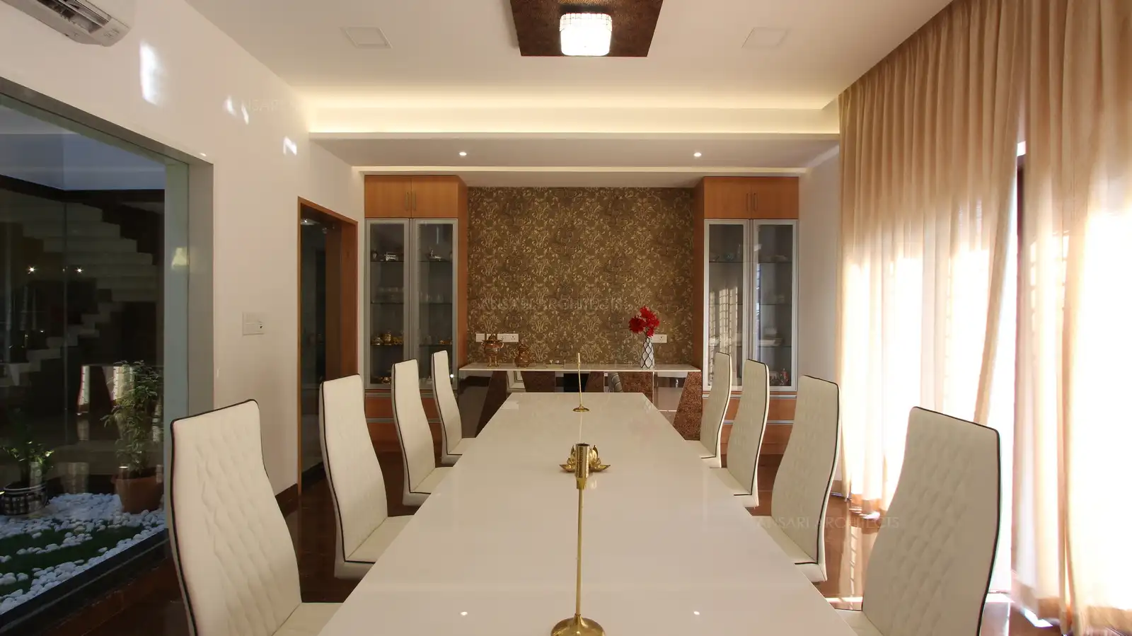 The dining features a accent wall consisting of wallpaper with golden hue and storage units with wood tones for a natural feel, the wall to ceiling grids are filled with crockeries and creates an uncluttered look.