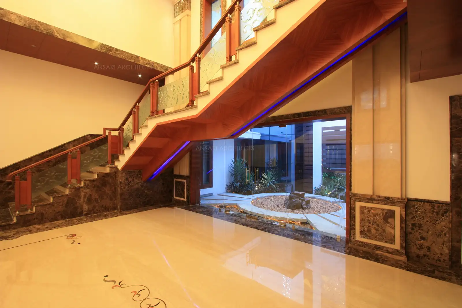 Wooden panelling used below the staircase with concealed lights helps to brighten up the area and highlight the view of courtyard.
