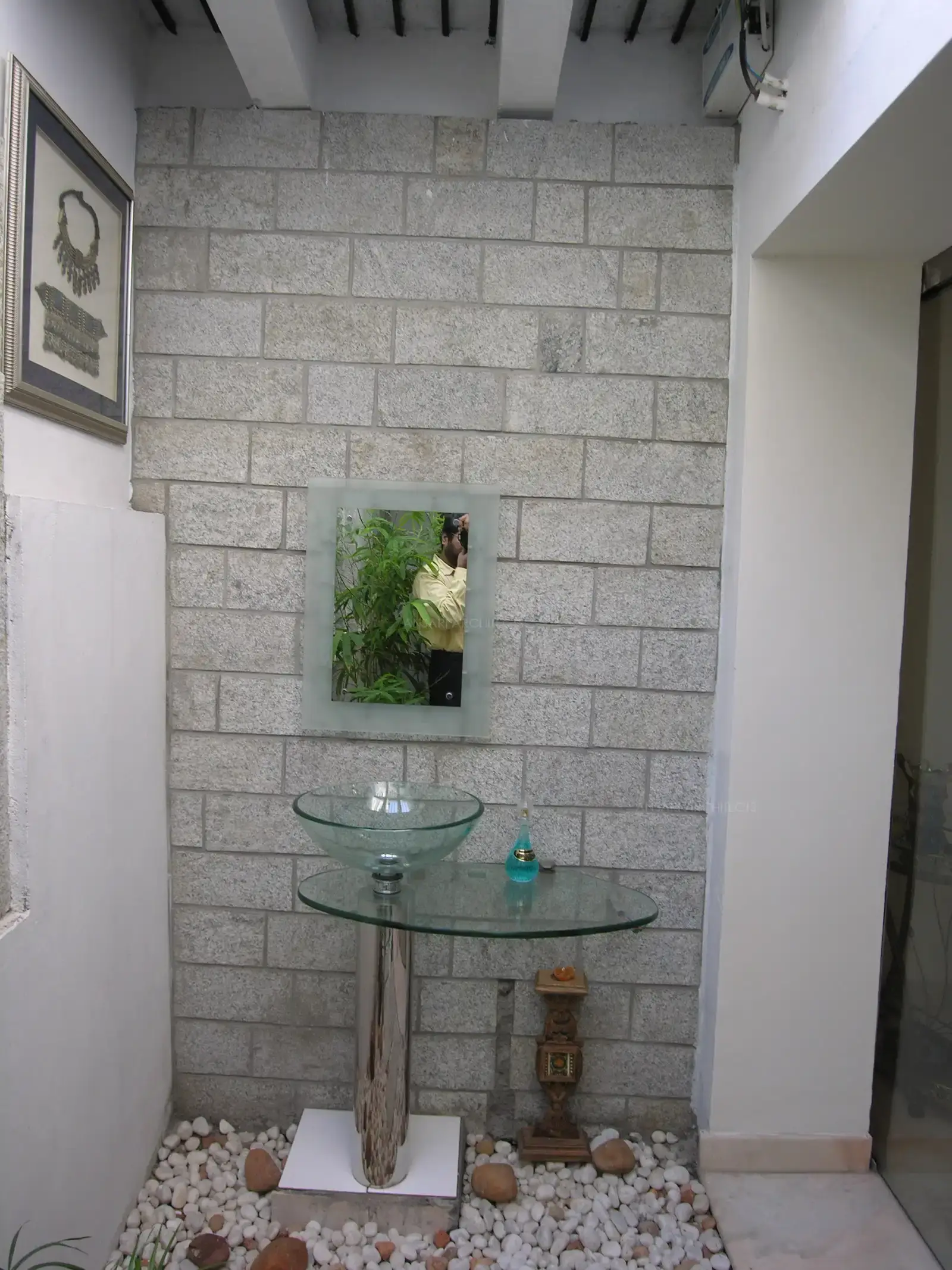Wash basin planned in dining courtyard with stone clad wall backdrop and pebble flooring.