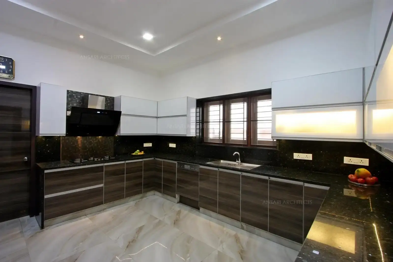 Modular kitchen area is punctuated with neutral scheme, the waterfall counters trend and the spotless cabinets give a clean look. The laminated cabinets which provide a rustic feel, granite top platforms bring warmth to the crisp white setting ,the backsplash tiles accents this kitchen. Hidden lights under the overhead cabinets add to vivacity.