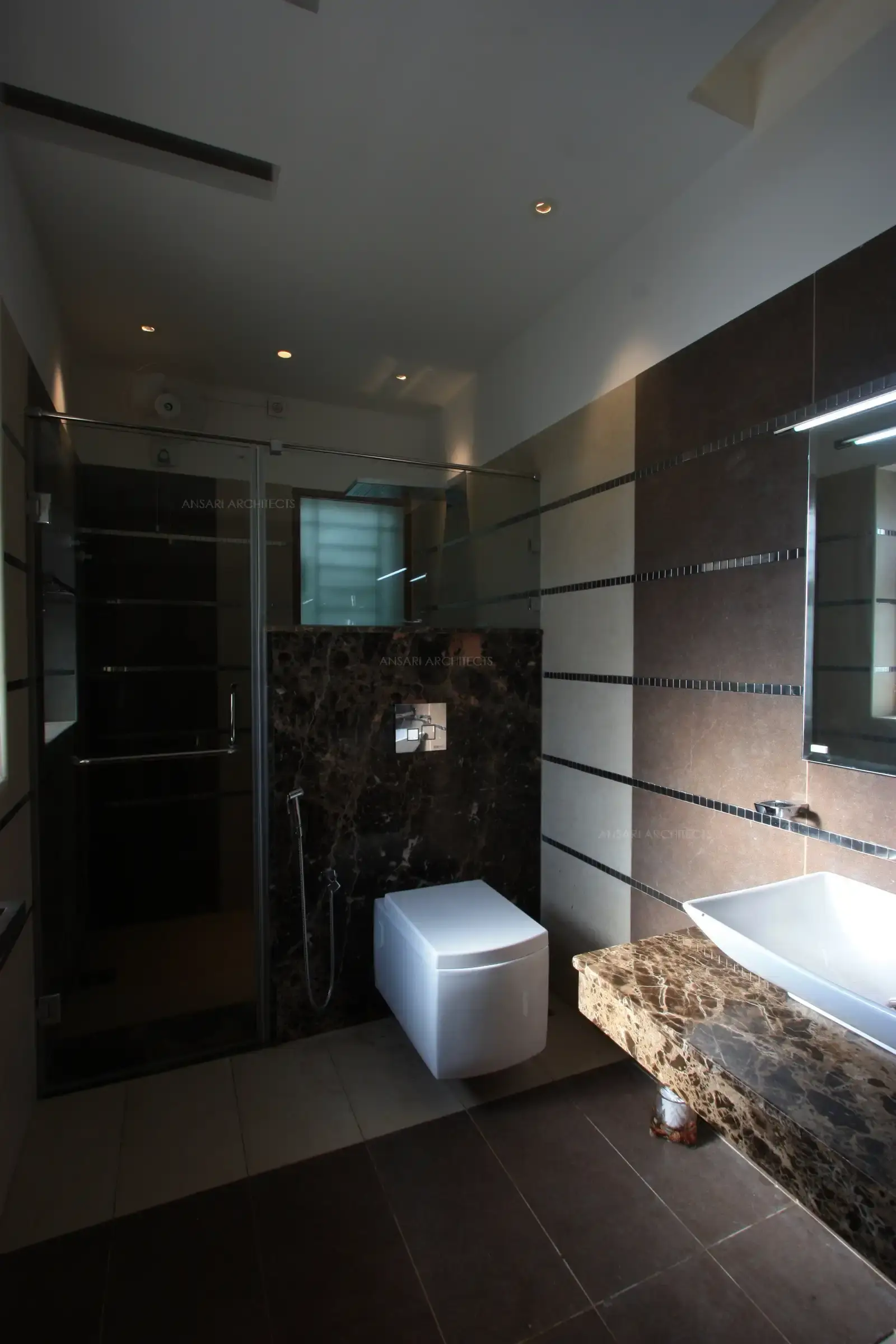 The toilet of master bedroom has two toned tiles with contrast granite in functional areas.