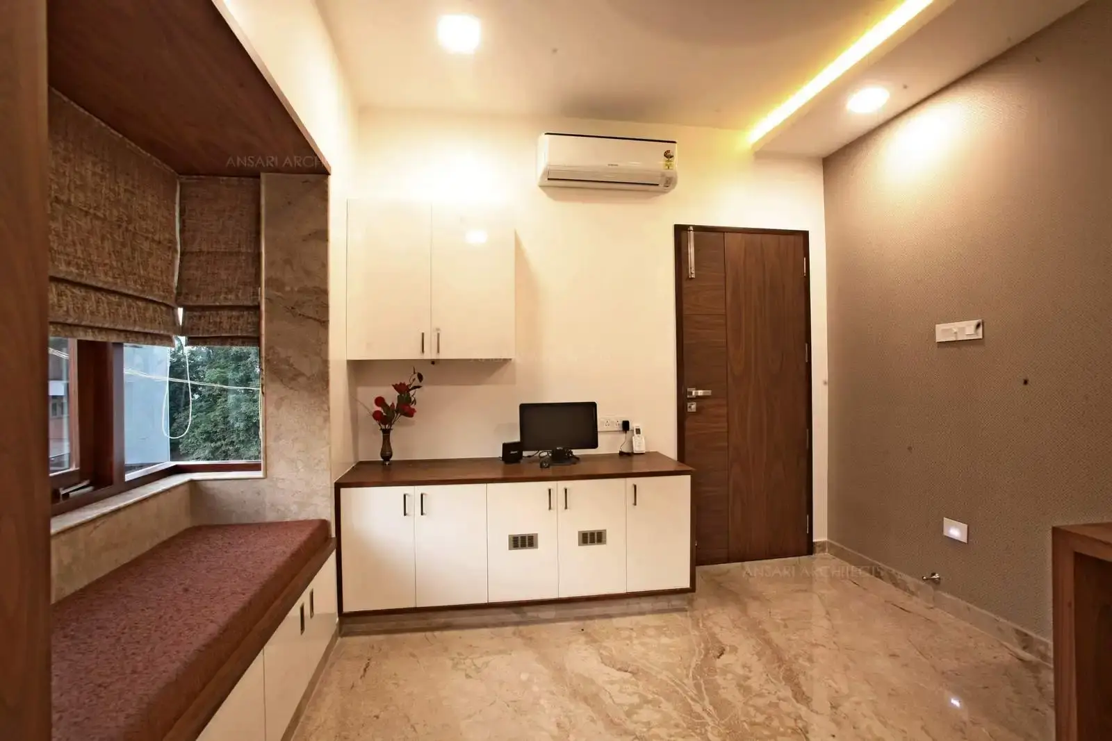 The luxury of merging the pooja and study transforms it to an interesting space. The room is setup with sitting window inviting in natural light, a wooden seat is created to the level of the window, beneath the seat comprises drawers for easy accessible storage. Serene and reflective space for a perfect pooja spirit. The feature wall in wallpaper with marble flooring. The storage cabinets hold a floating base with neutral white.