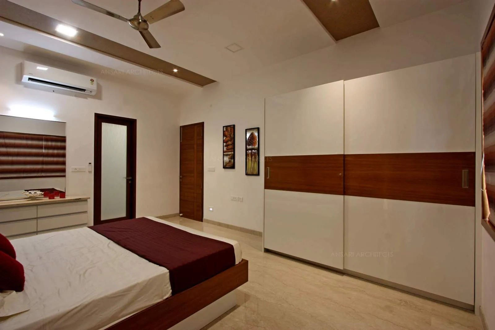 Artfully styled wardrobe units standing tall with the white walls adding a touch of warm wood tone, ceiling has a mellow palette of beige inset lighting, photo frames keep the ambient relaxed.