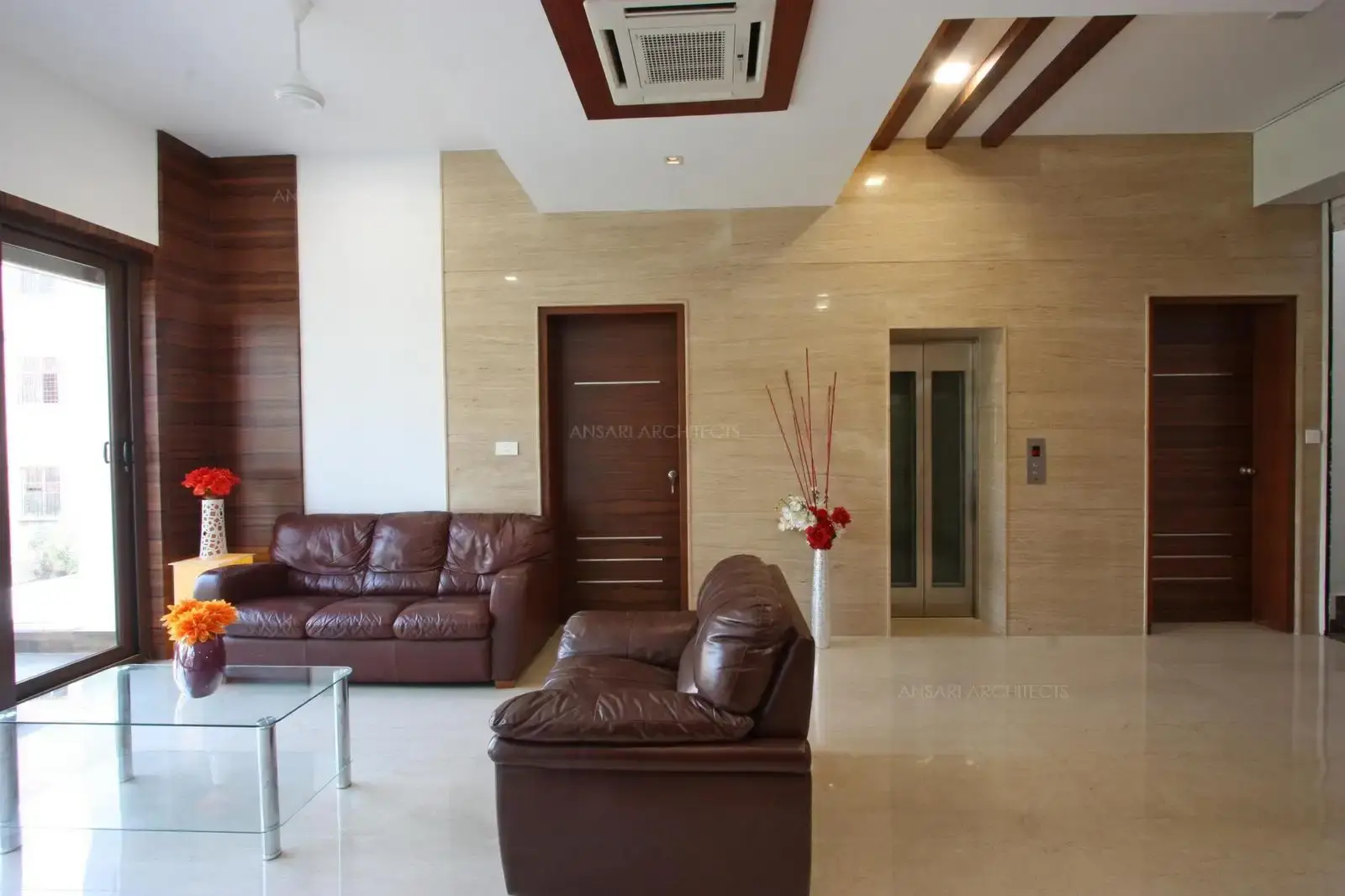 Marble cladding and veneer panels balance the warmth of the room. False ceiling has an intimate feel along with the white walls add to a sophisticated look.