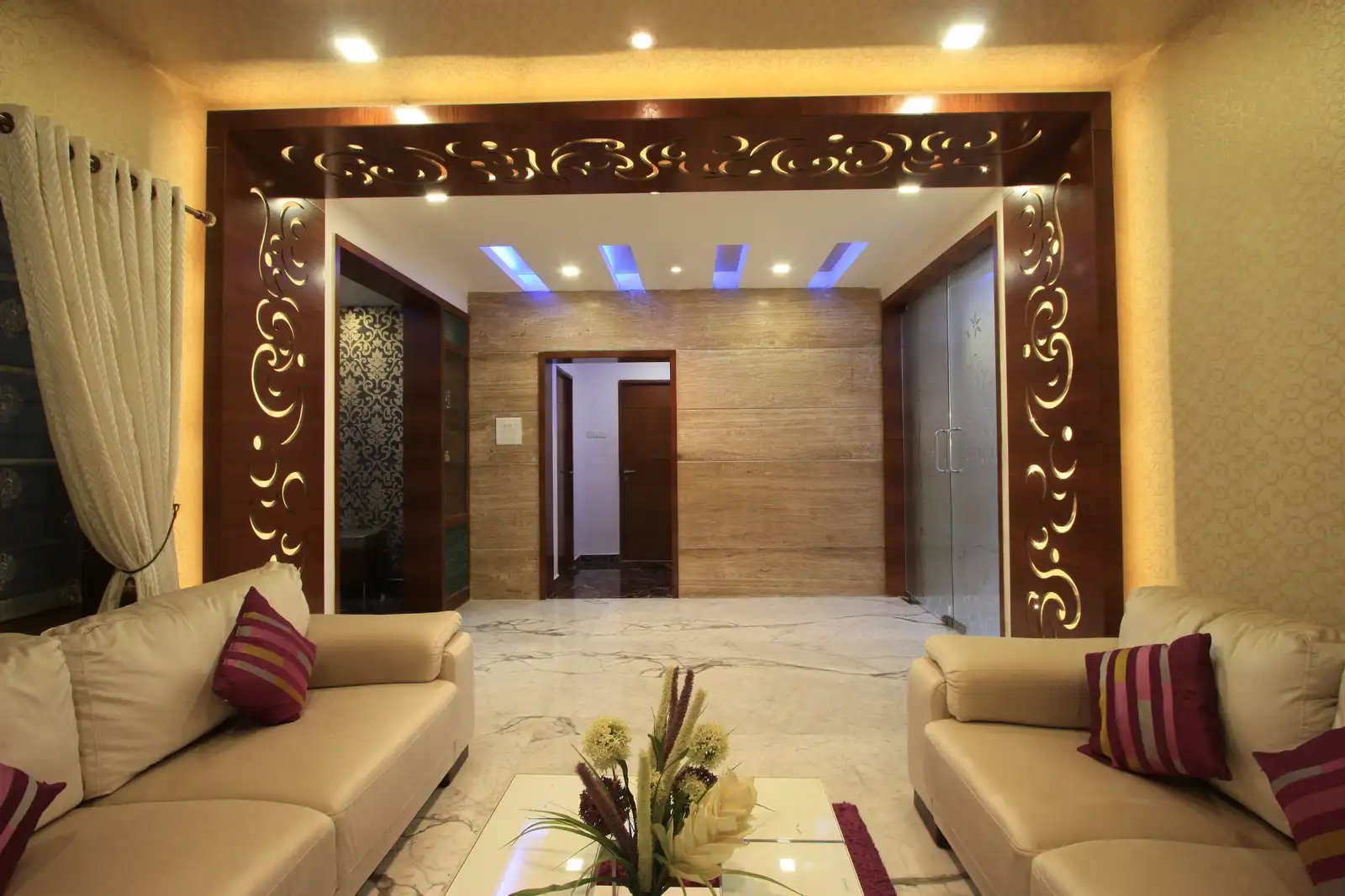 Wooden panelling arund the opening and marble cladded wall on the other side with concealed lights on the false ceiling makes this entrance bright and inviting.