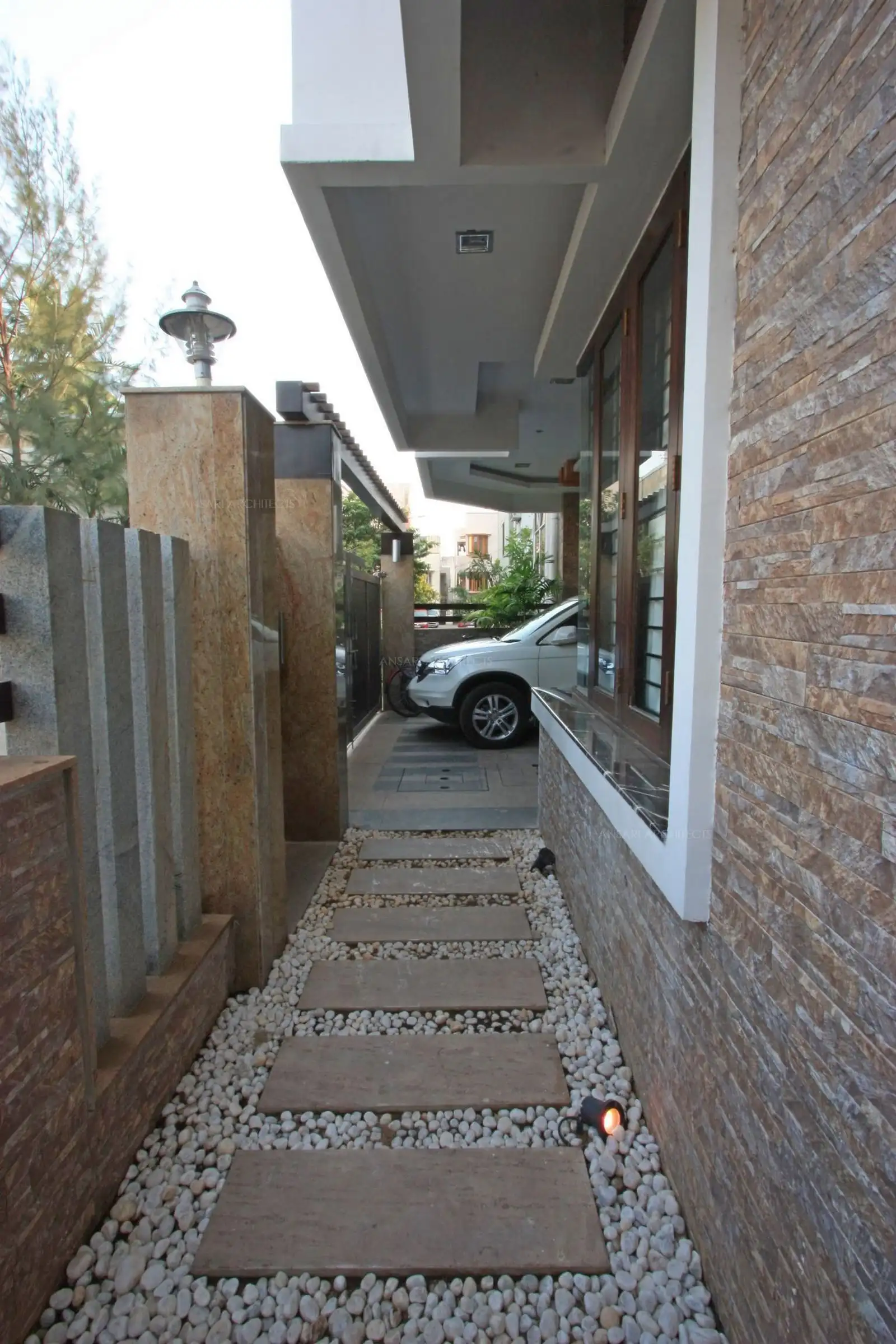 View of the pathway and compound wall which has been designed well to go with the exterior finish of the house.