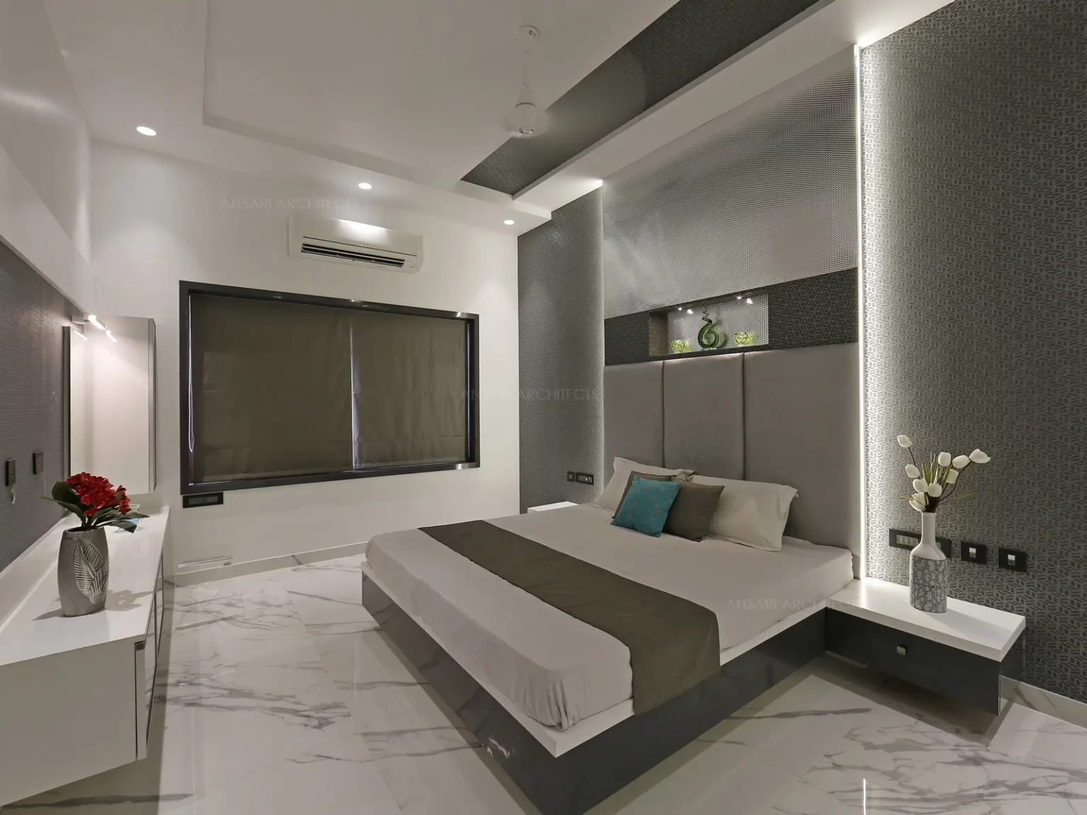 The yin and yang based counterbalancing collision of grey and white gives a contrasting vibe. The panelled wall with cool grey tones and slender furniture with storage. Wardrobe unit with full width of the wall maximises storage and creates a visual feature. Also mirror finish is an attractive way to visually increase the size of the room.