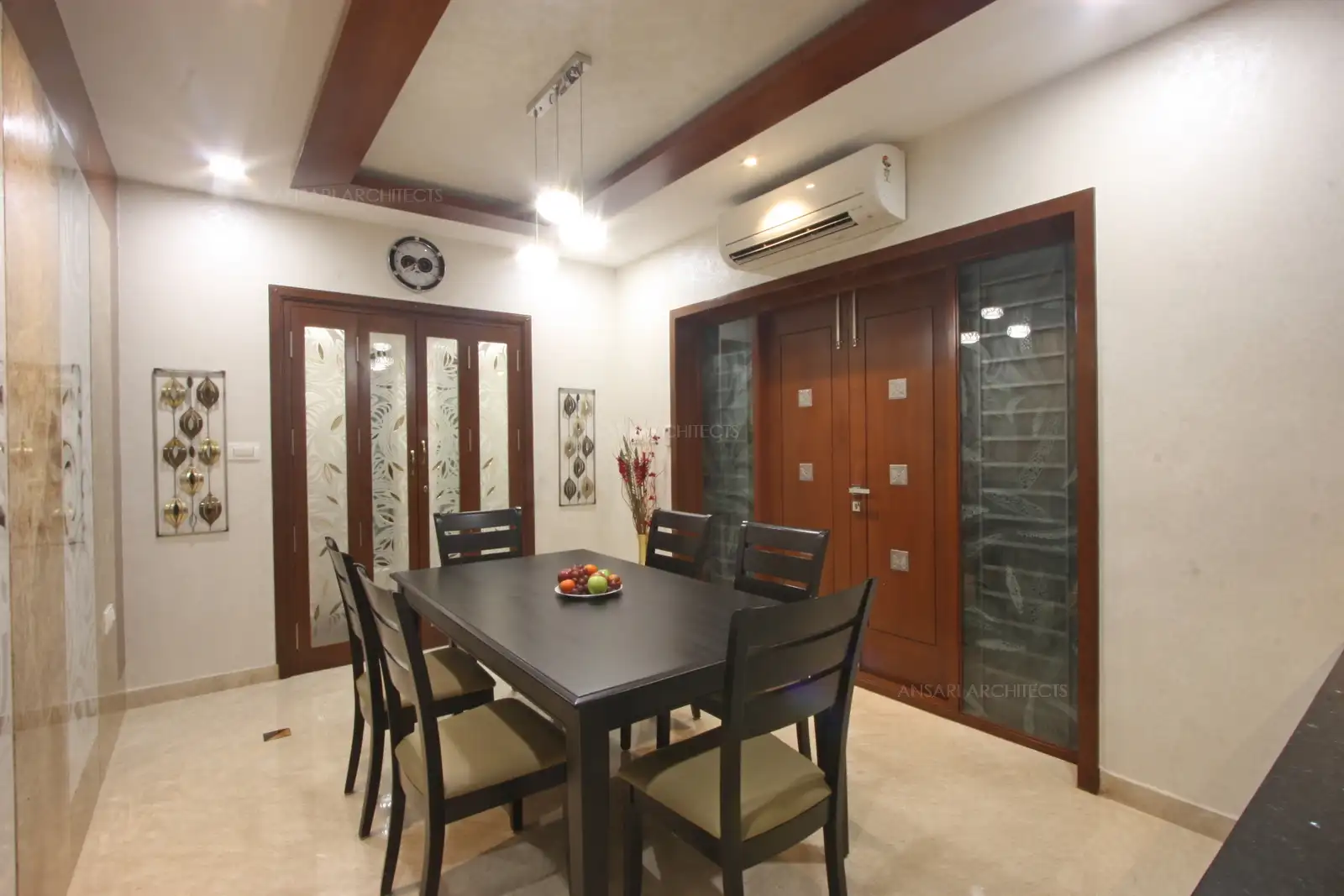 The neutral palette is elegant with leather upholstered chairs, and polished wooden black table. Pendant lamps add a contemporary touch, the solid wooden doors provide warmth.
