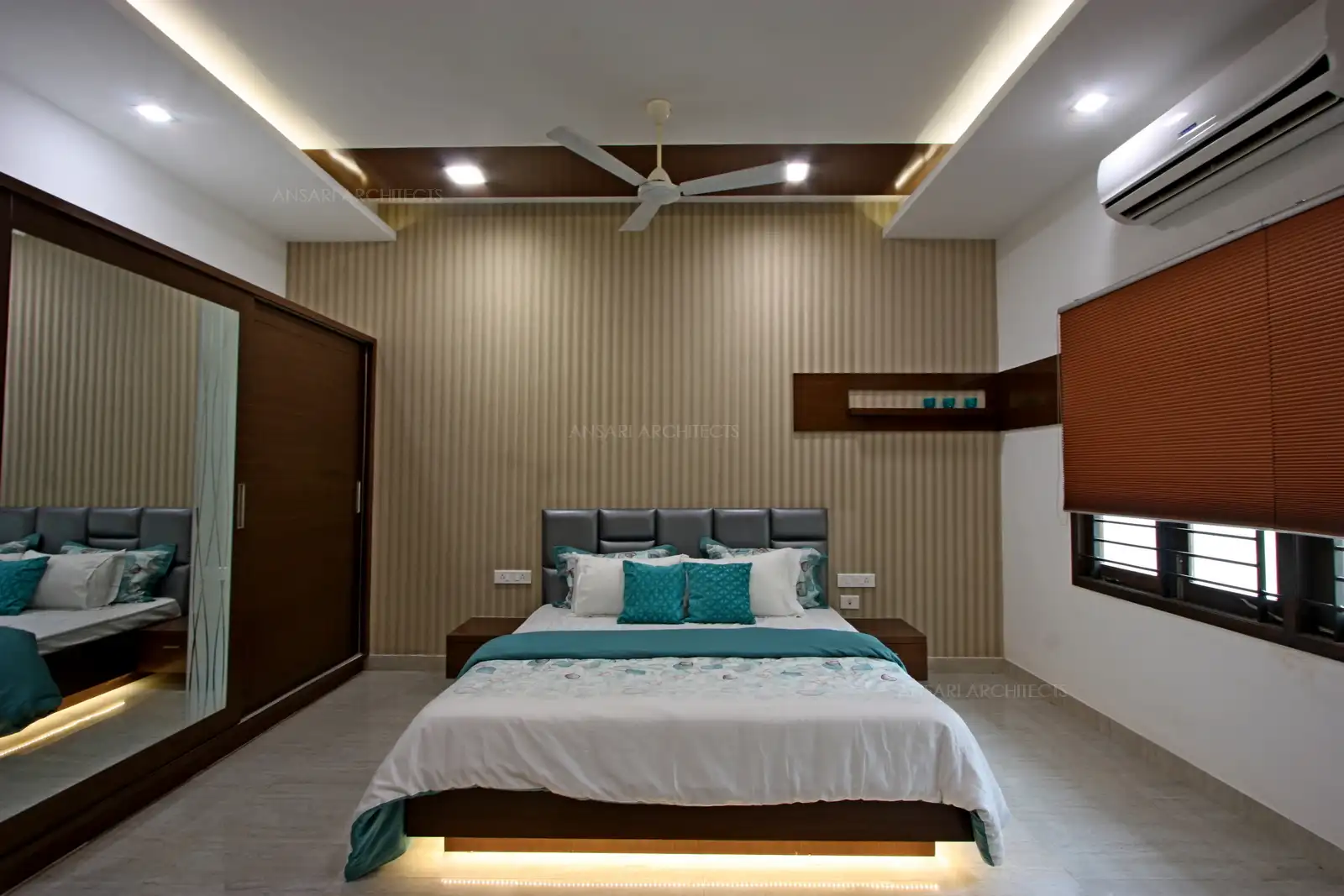 Wardrobe with sliding doors and mirror with wooden panelling and false ceiling highlights on either side of the room.