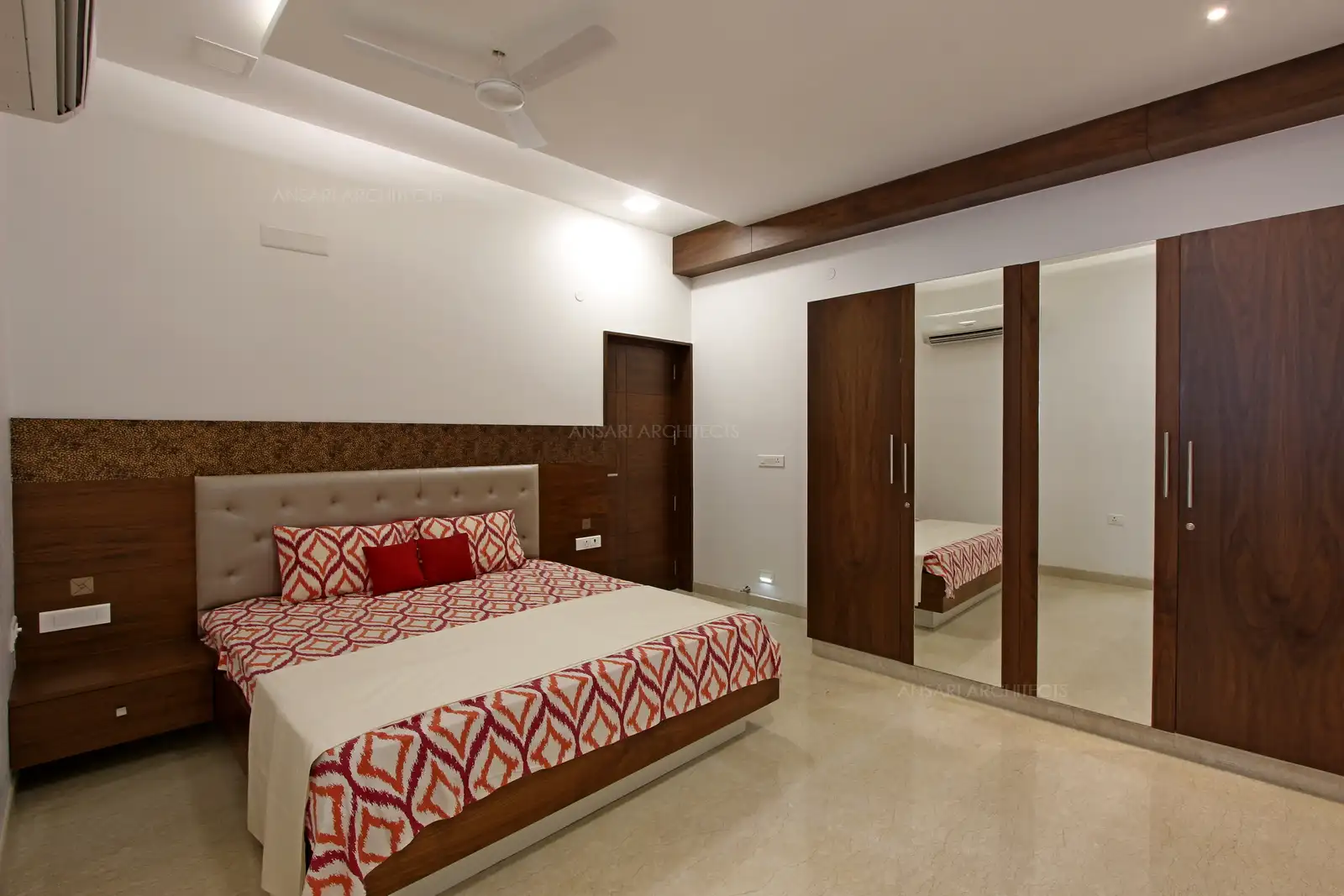 The wooden beams on the ceiling provides a vintage finish to the space. The dark hue is offset with soft recessed lights , giving the space a warm and inviting vibe. Laminated wardrobes offer the desired finish highlighting the contemporary twist.