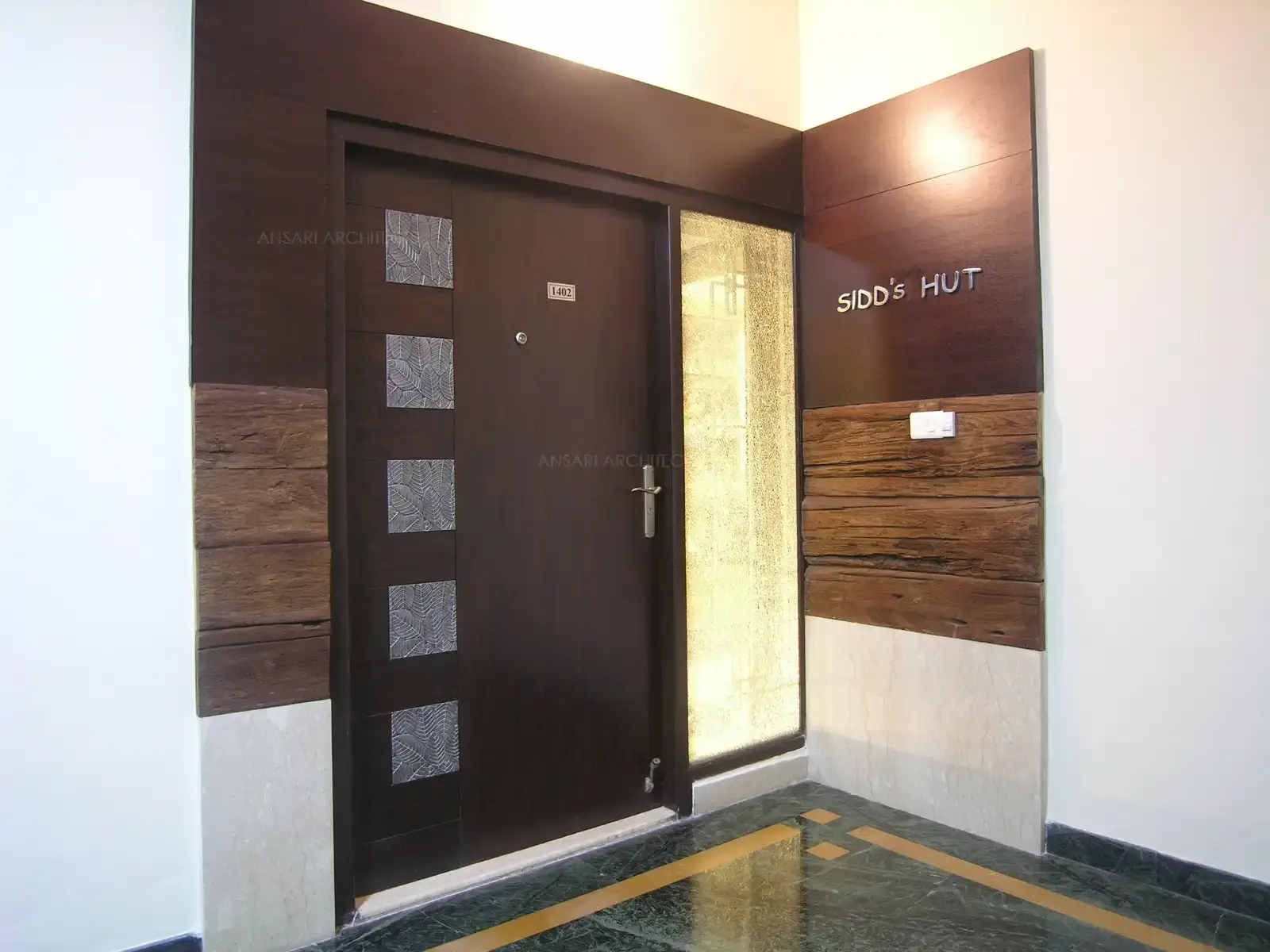 Main door at the entrance has been designed with artistic metal in inserts surrounded by wooden wall pannelling from outside.