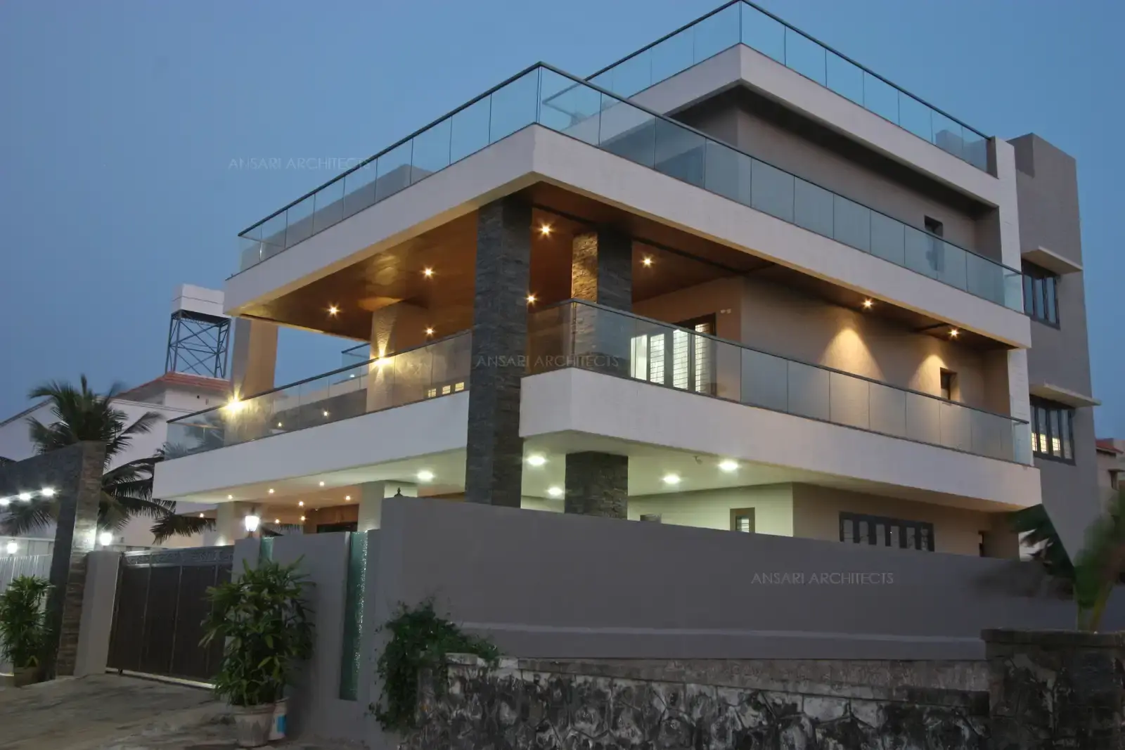 The facade is contemporary, characterised by clean, straight lines accentuated by soft glow of recessed lights and glass. The massing looks interesting with bold architectural elements.