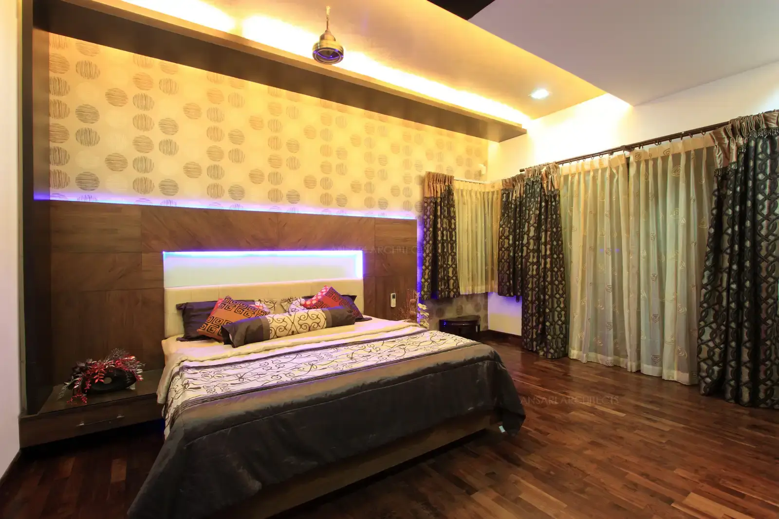 Wooden panelling with conceal lights and wall paper highlight the bedside wall.