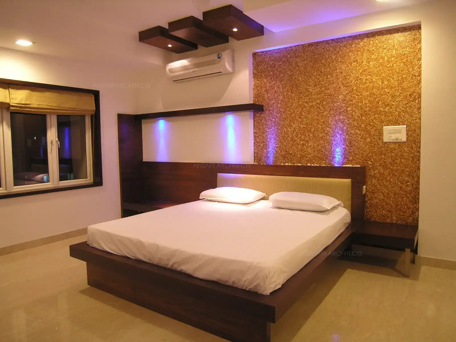 A small depression in the wall of master bedroom was turned into a focal point with wall paper and wood panelling behind the bed with spot lights.