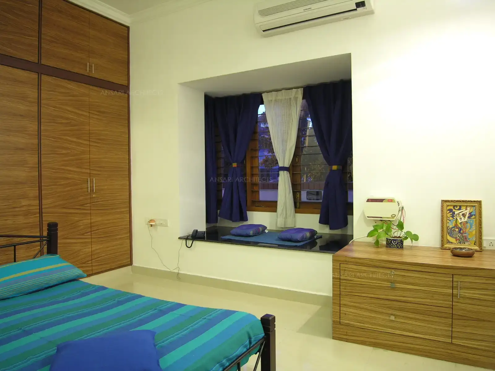 Daughter-1's bedroom in the first floor has a 'Sitting Window' designed with white walls in contrast to blue furnishings for a bright look.