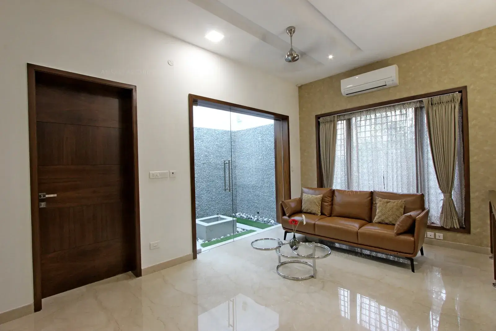 Family room with courtyard view, sunlight rushes in through the glass door with highlighting the wall with wallpaper with distinct furniture and console table with metallic rings and glass kept the design language flowing and curtains combine various styles.
