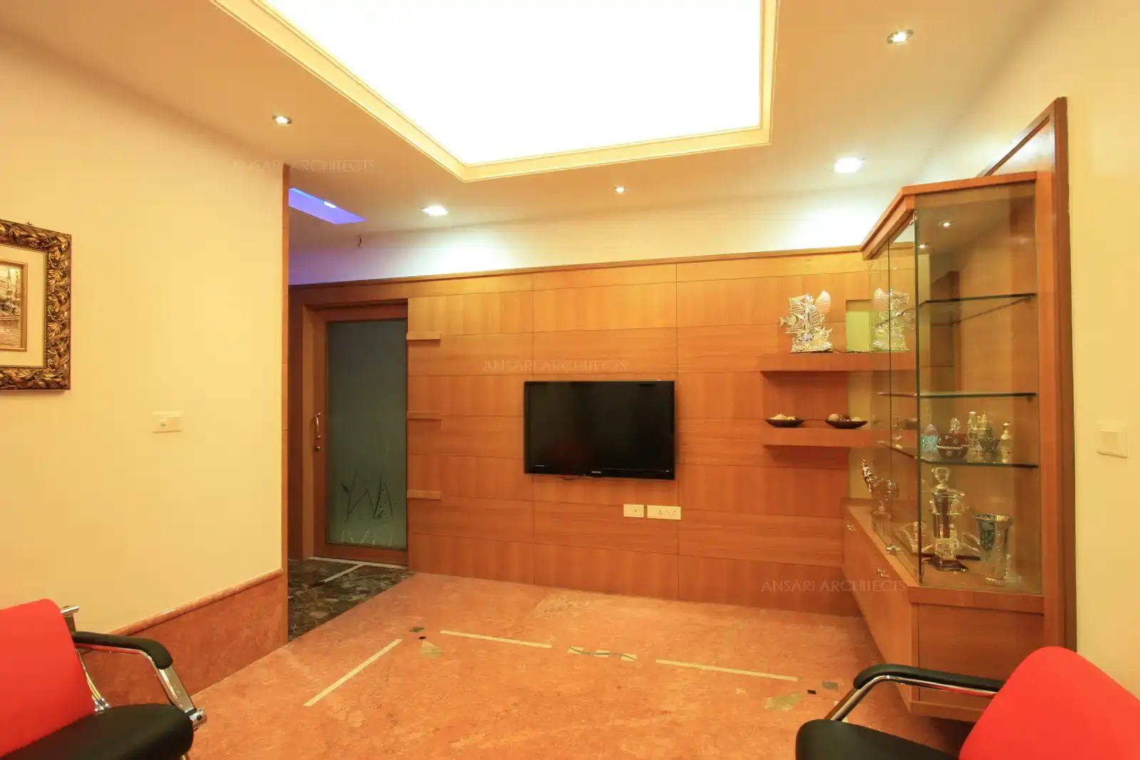 View of lounge area showing the TV on rich wooden cladding and display unit.
