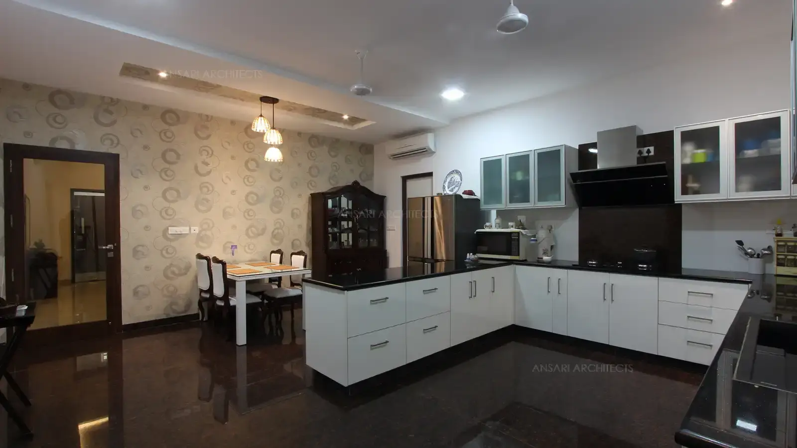 The kitchen features in dining area with vibrant furnitures. The modern breakfast table ties in cohesively with the colour scheme of the rest of the kitchen. The granite table top is a inspired solution here, wallpaper wall with pendant lights enhance the dining.