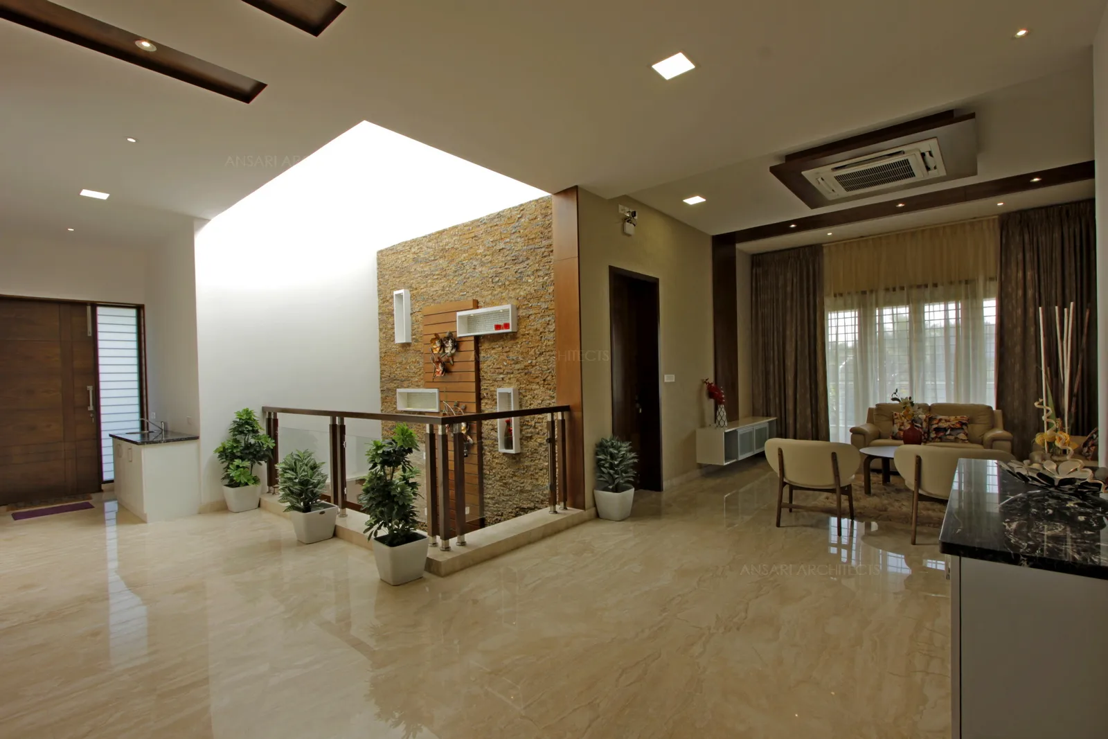 Family area with recessed inset wood texxtured ceiling with soft recessed lights. The glass handrails overlook the courtyard with plush green highlighting the space.