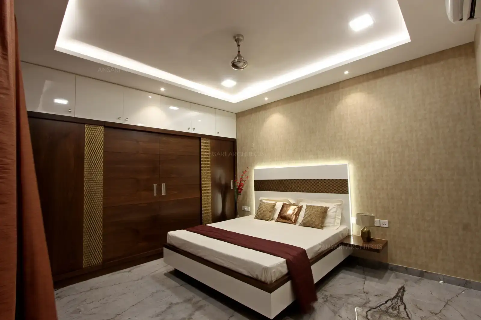 The bedroom with wallpaper elaborate wall, headboard contrasts with gold floral carving and backlit for a majestic look. Highlighted wall sconces, with decorative marble flooring.