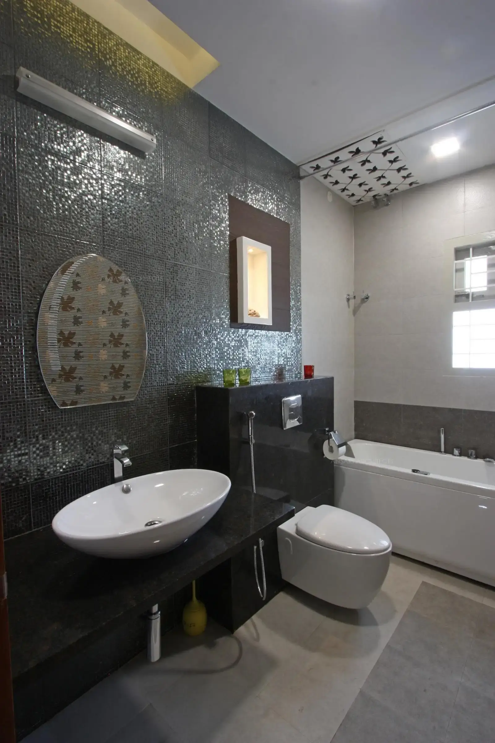 A more subdued version of vanity, the granite counter and the mirror blends into grey backdrop ,the niche creates in a element of interest by adding lights. Shower area is separated along with the grey tiles creating a confined space.