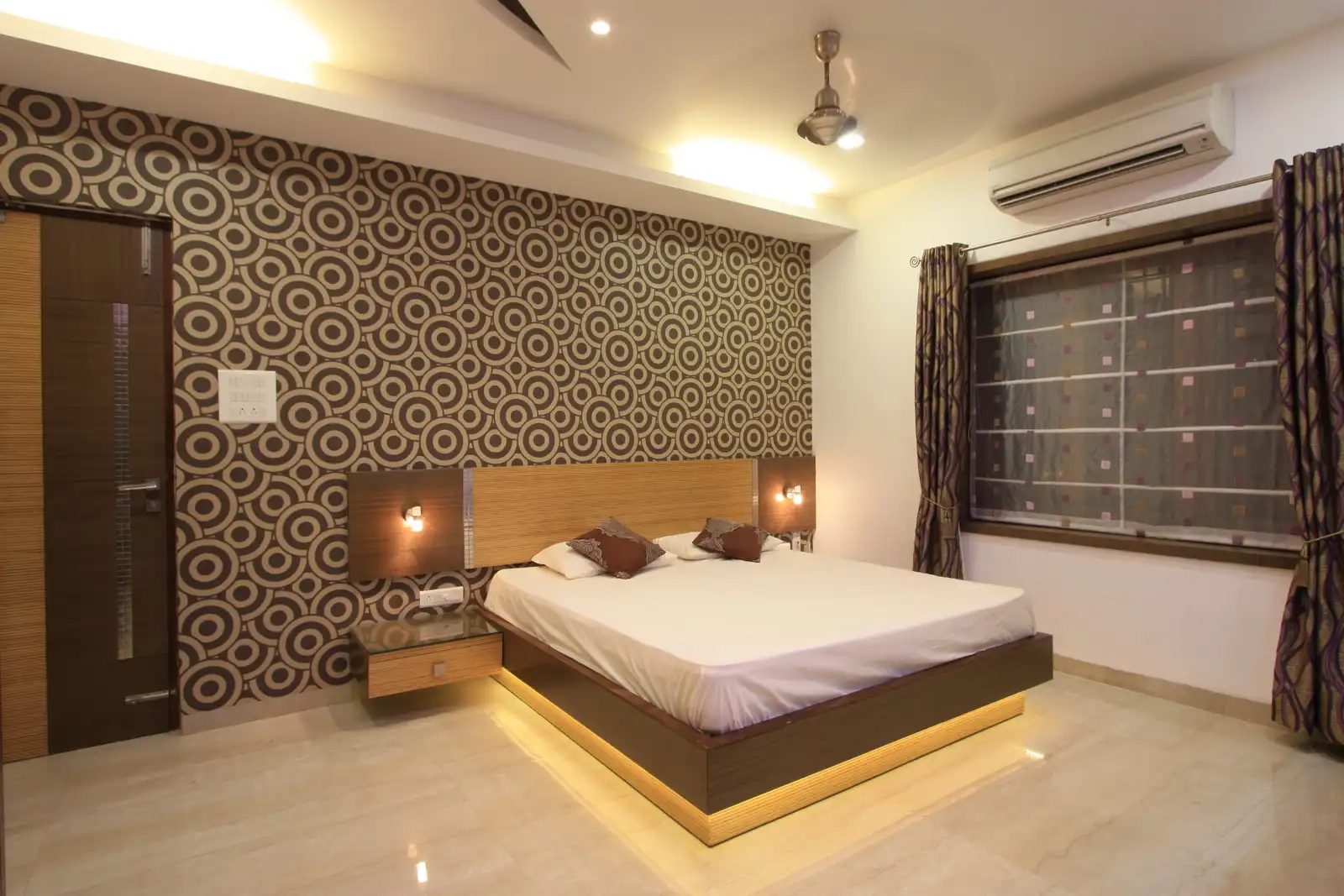 Bold wall paper dominates the bedside area with silver highlights used along with the veneer.
