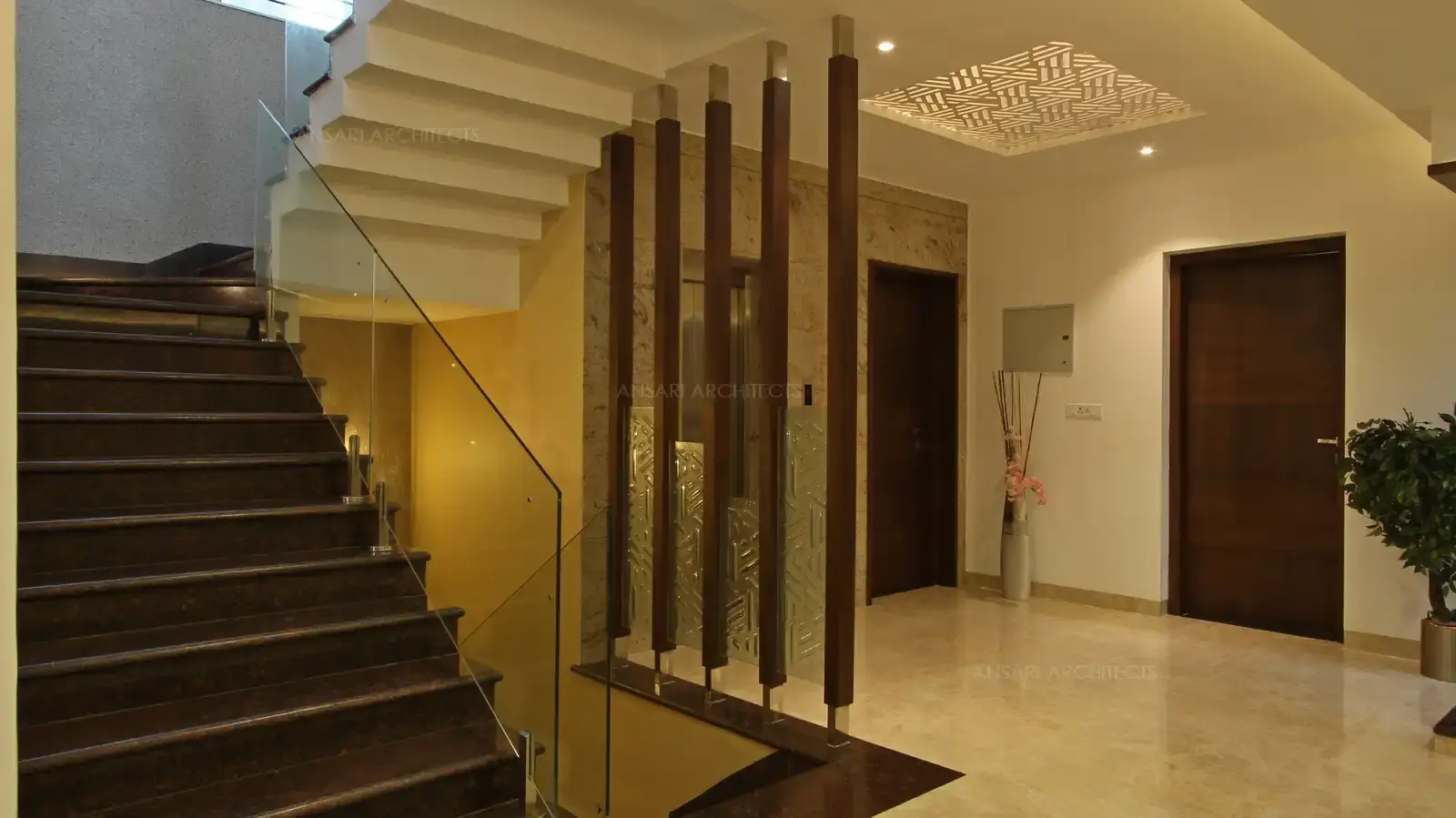 An open landing is converted into a beautiful lounge space. Wood battens here with glass acts as an obstruction here for the staircase space, decorative panels are used for the ceiling to provide a visual appeal.