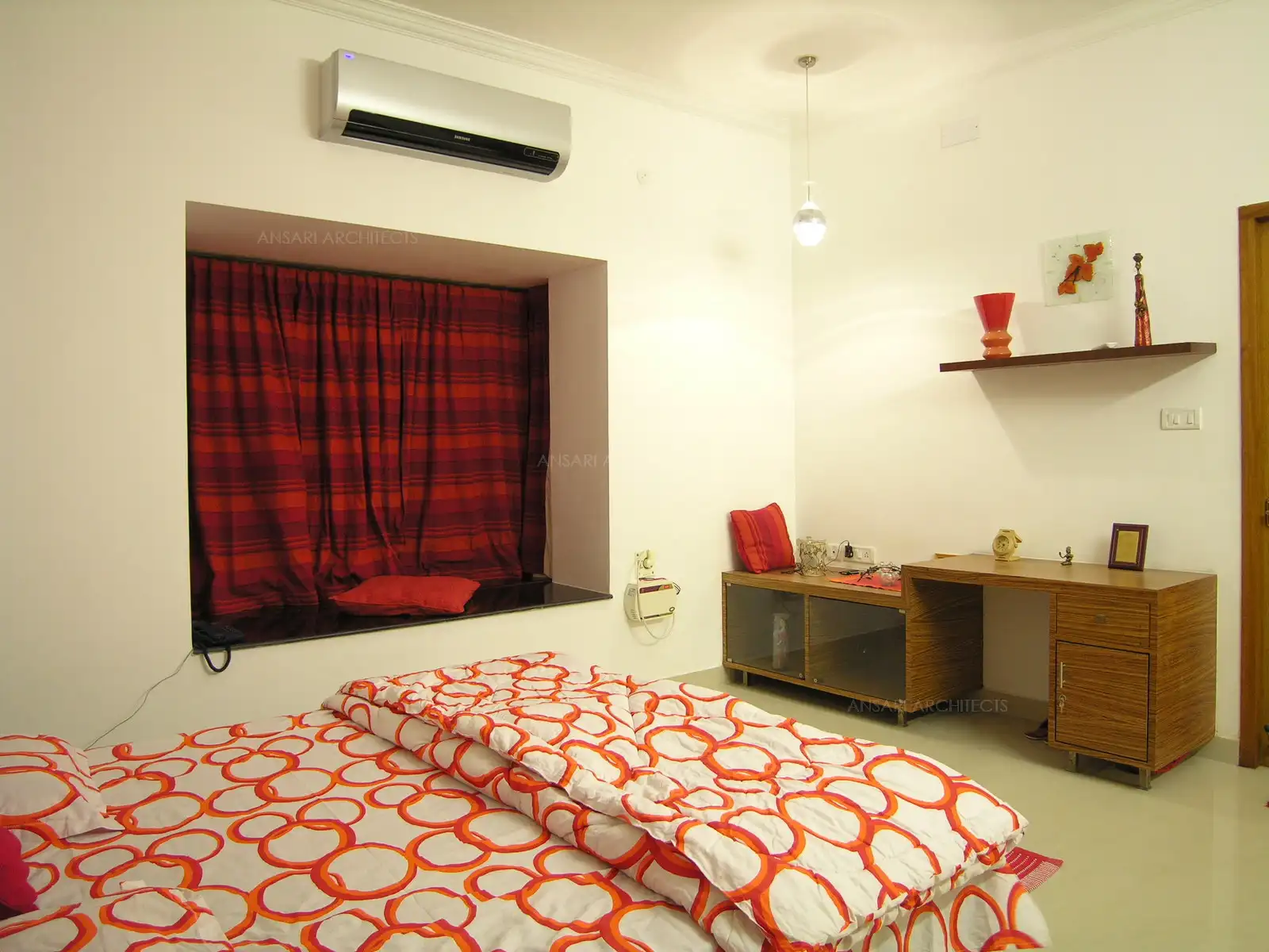 Master bedroom in the first floor has highlighting red and orange shade brought in in through furnishings and curios.