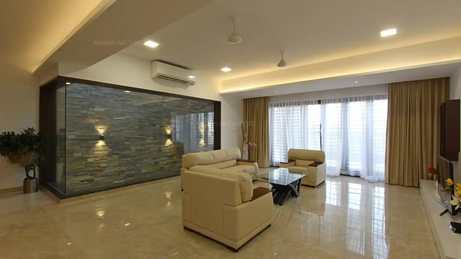 Family room with relaxed seatings, a sleek console table in glass with marble flooring along with recessed lights makes the room a great space for luxury and ideal design.