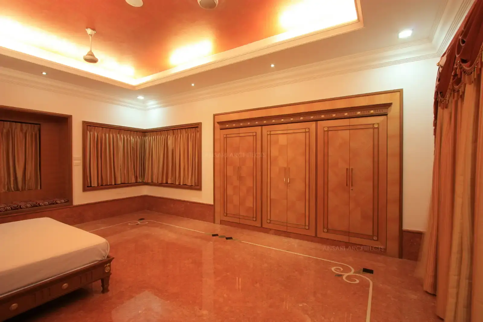 Wardrobe is deigned to be in flush with the wall with golden cedar veneer and metal inlays in the cornice above.
