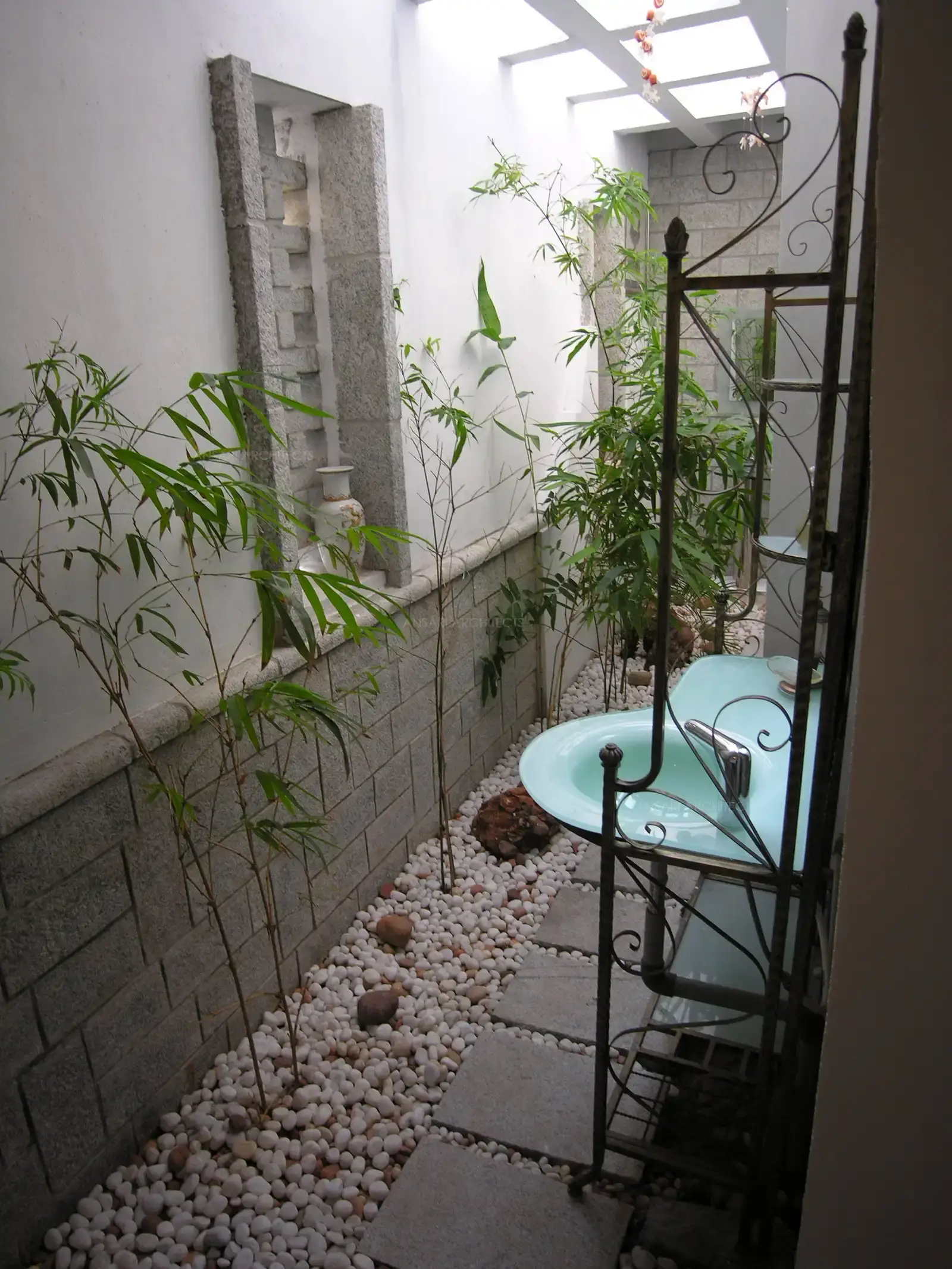 Courtyard designed in stone clad wall and pebble flooring with with simple bamboo trees.