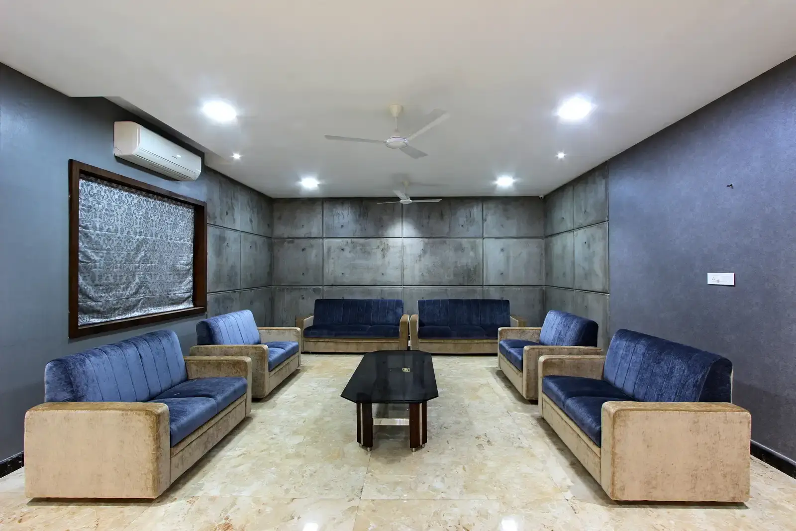 The family room is perfect bliss with concrete textured tile along with shades of blue accentuates the space. The glass top table with light fixtures and flooring complete contrasting the walls creates a modern outlook.