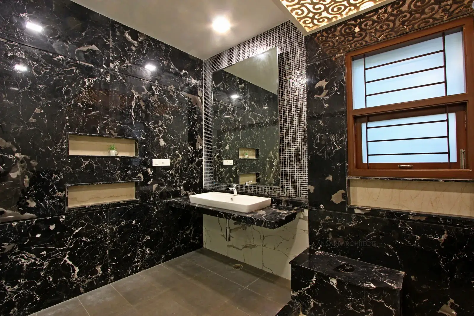 The tile creates cohesive combination with surface mounted basin, a custom-made vanity unit with large mirrors. Rich tones sit beautifully and backsplash tiles creates contrast. Decorative panels in ceiling used for lighting.