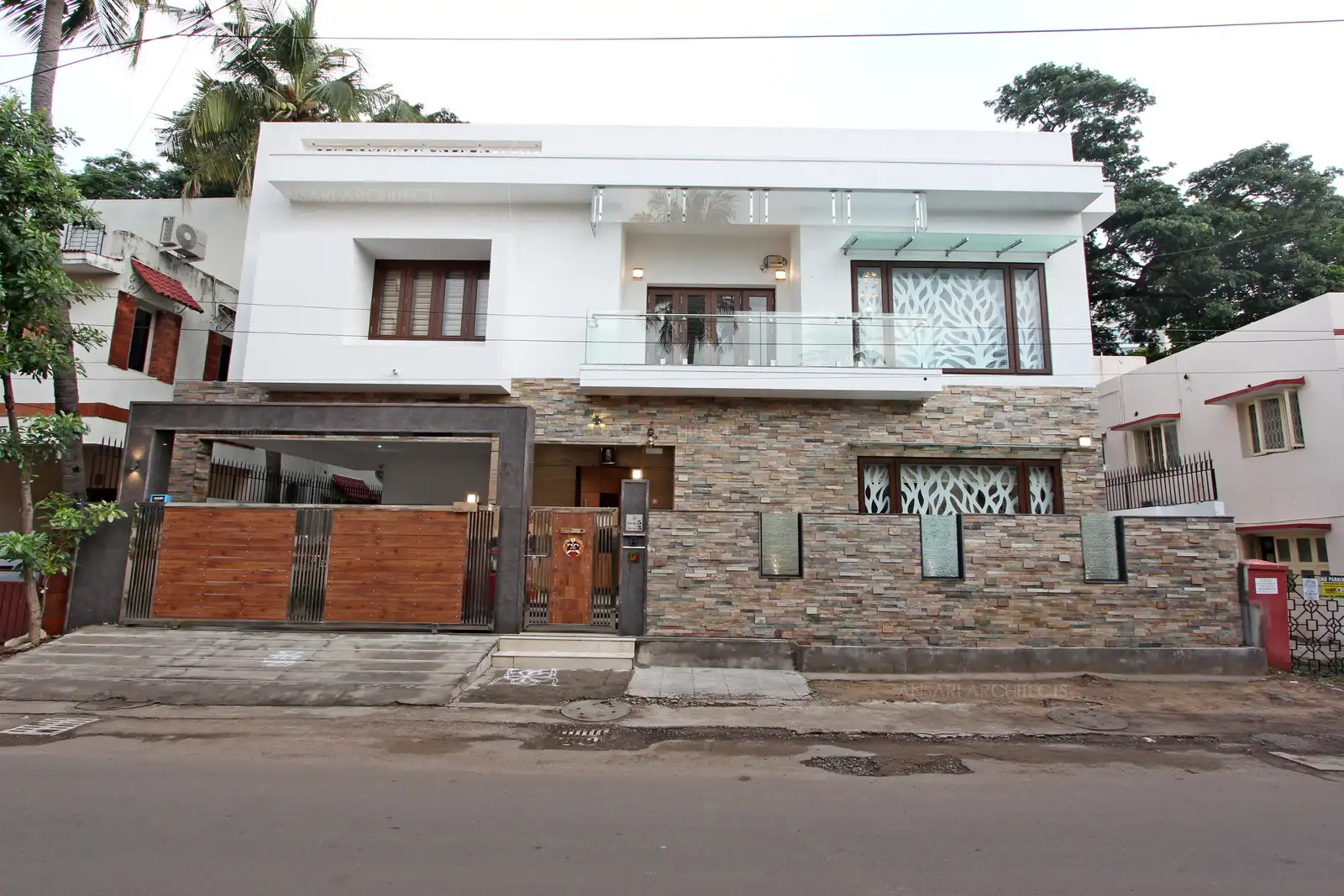 The building's exterior shows clean, strong lines that give the home a bold appearance. The building shows an earthy feel by the intriguing mix of materials, whilst the row of windows and cutwork create a dainty touch.
