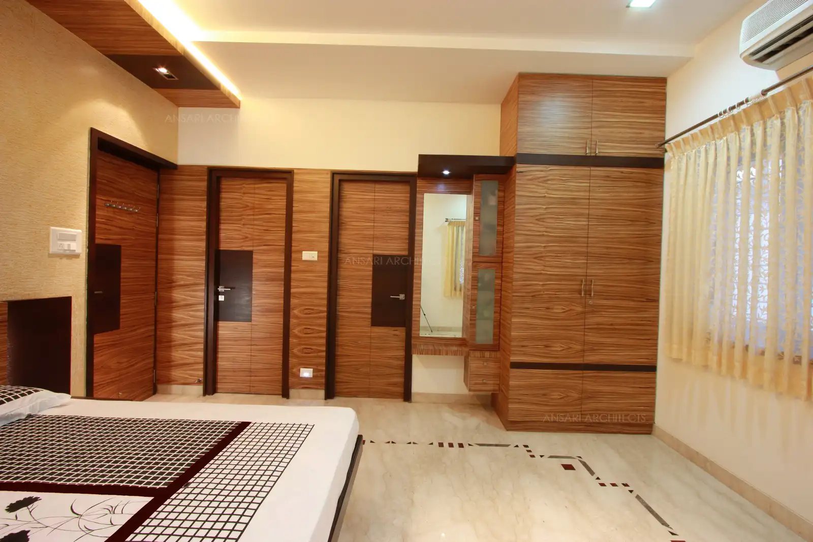 Horizontal grains of veneer is contined as wall panelling along with the doors and wardrobe to give an even look to the room.