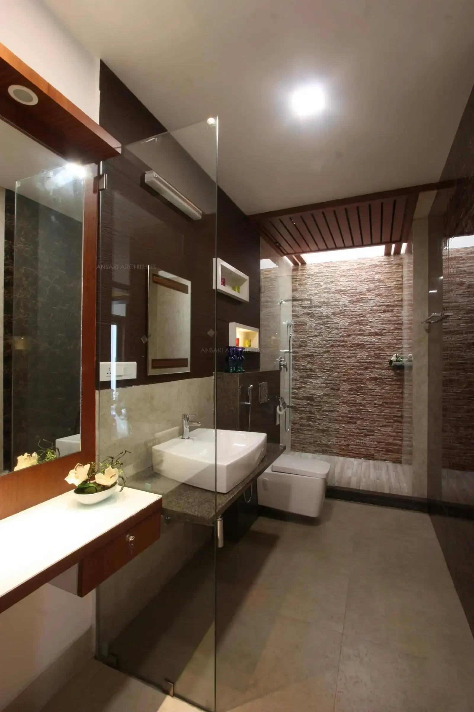 A lavish and expansive bathroom with the decor elements such as niches contrasting the panelling , The shower area is cladded with stone texture magnifying the sense of grandeur. The subtle use of textures and lighting creates a cotemporary class.