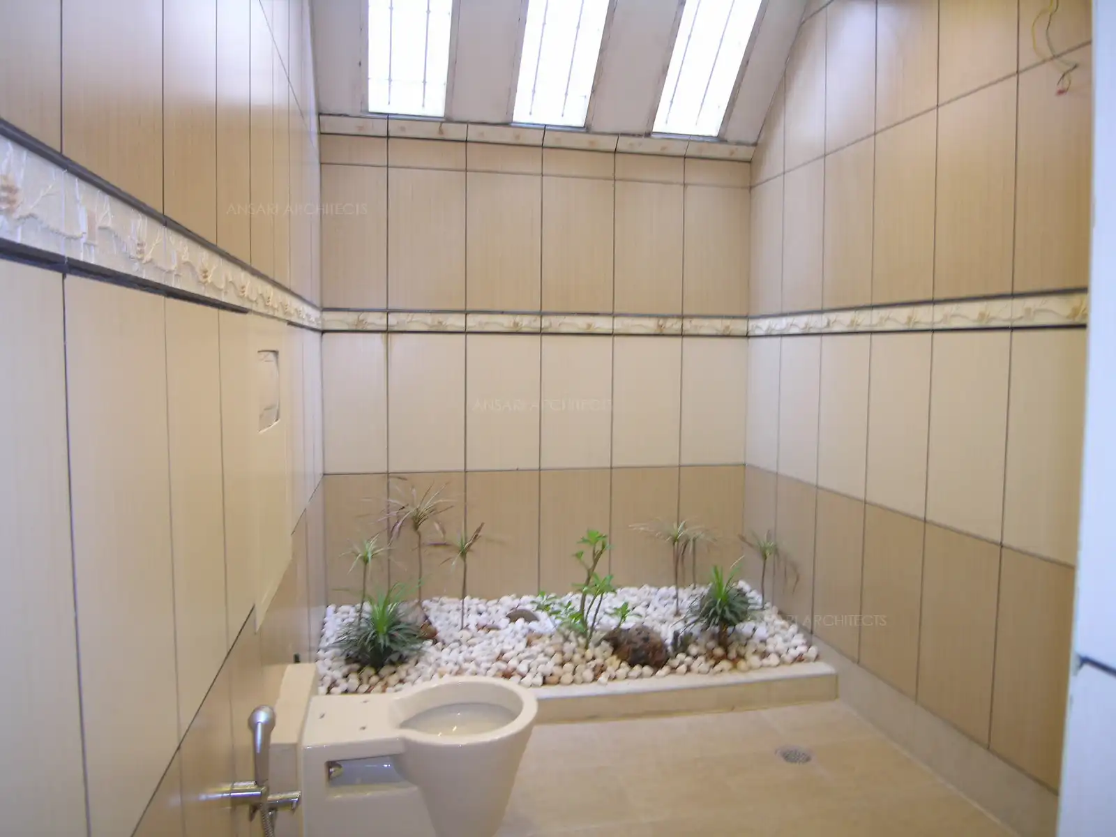 Powder room in the ground floor has sky light roof with pebble bed and plants below.