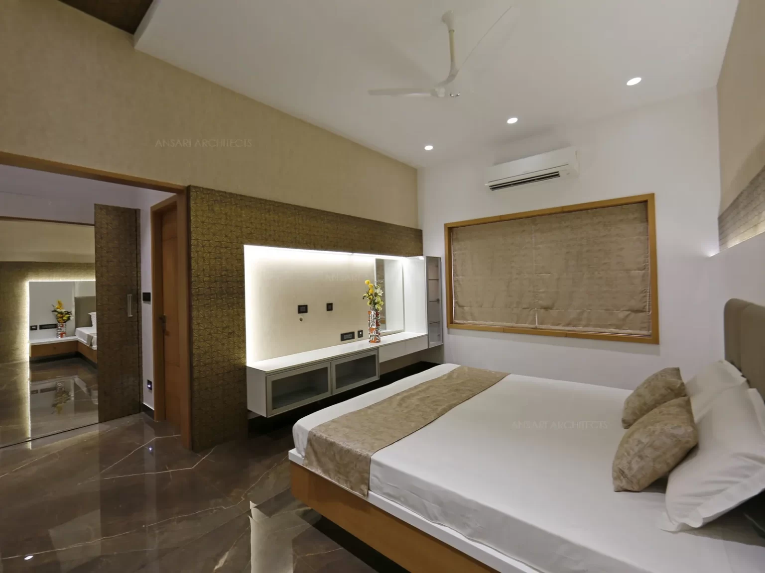 The muted white walls creates expanse of neutral colours and the cozy bedroom with soft light. The centre dressing table is an contrast with the panelled wall of subdued elegance.