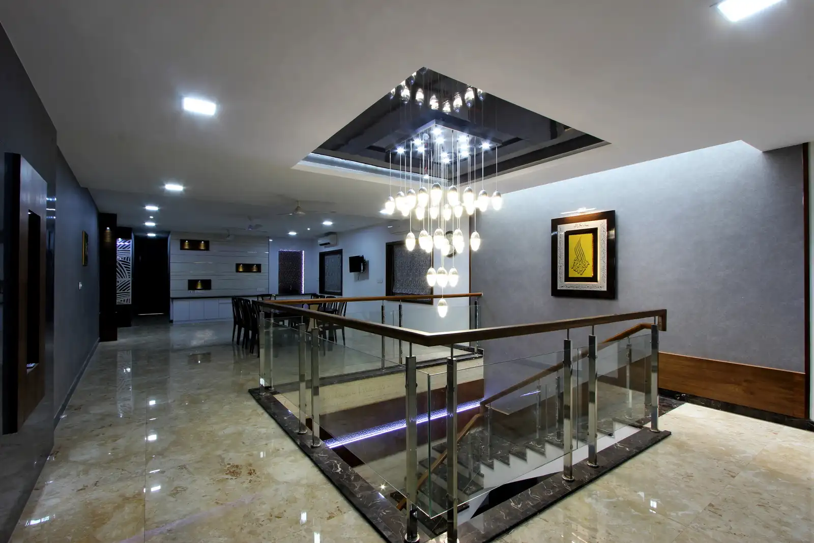 The staircase space defines lighting and creates a recessed ceiling inset with pendant lights.