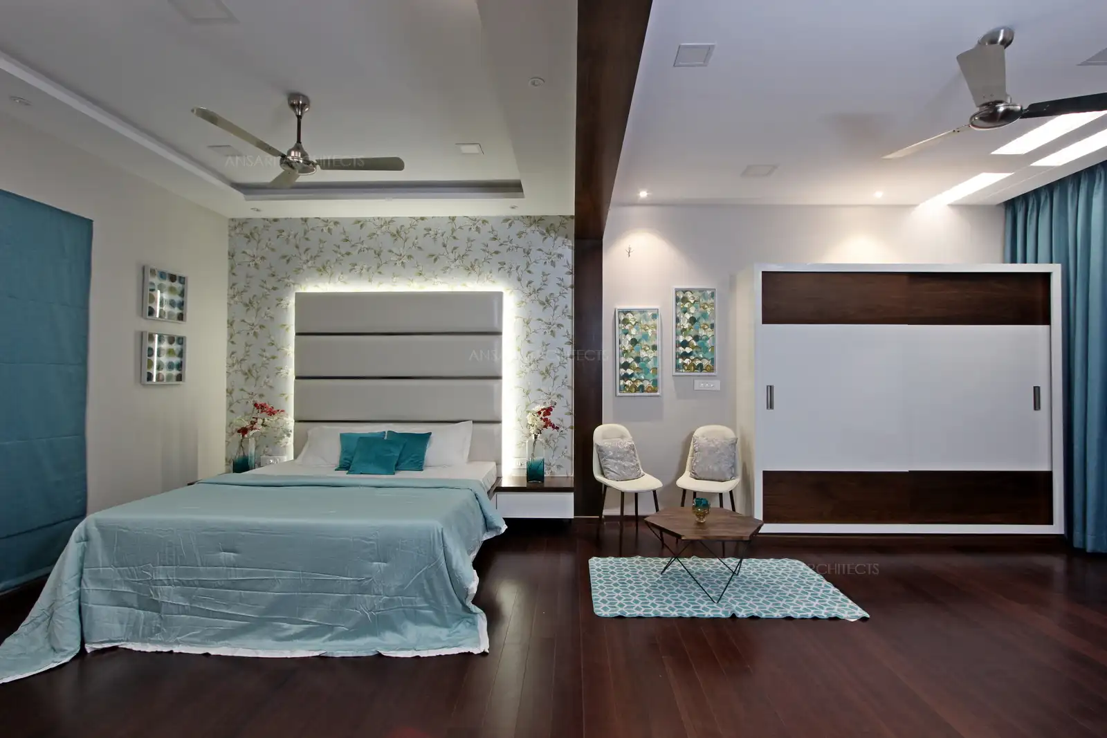 A bed with side tables is neatly tucked in cushion headboard backlit with lights simply radiates style. Wooden panels, wooden beading all combine to provide an interesting composition.