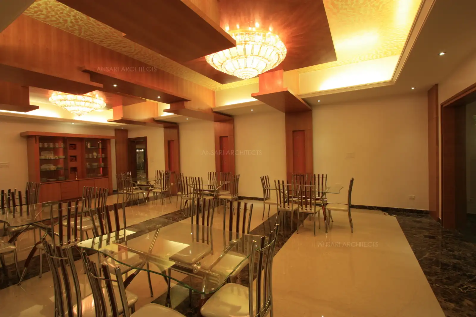 Chandliers used along with wooden false ceiling on a gold foil effect back ground define luxury with elegance in this formal dining room.