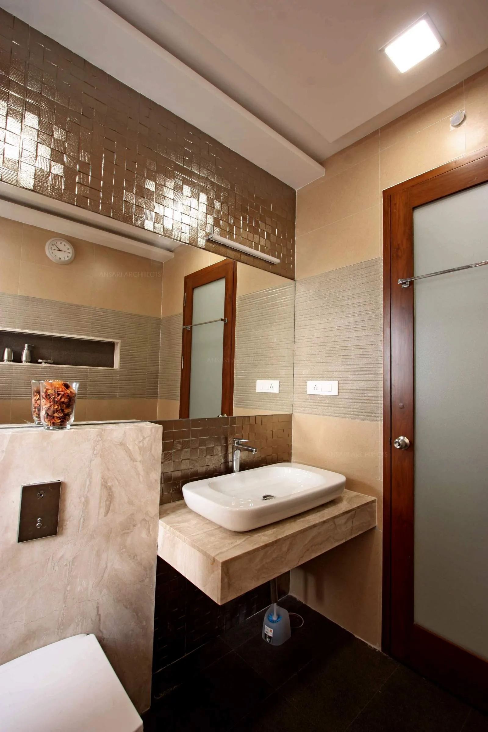 Vanity unit with large mirror, the wooden texture and the backsplash patchwork tiles that sparkle with the recessed light glowing provides a harmonious vanity space.