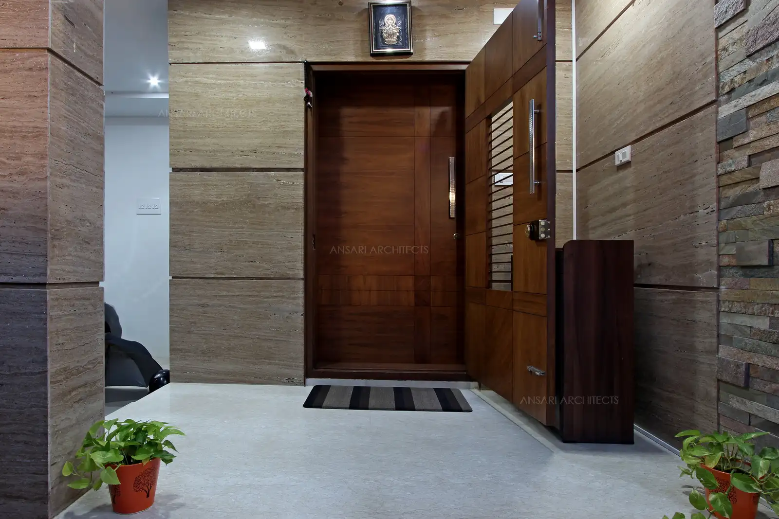 The entrance is cladded with marble with solid veneer door. Landscapes soften the textures and the space remains subtle.