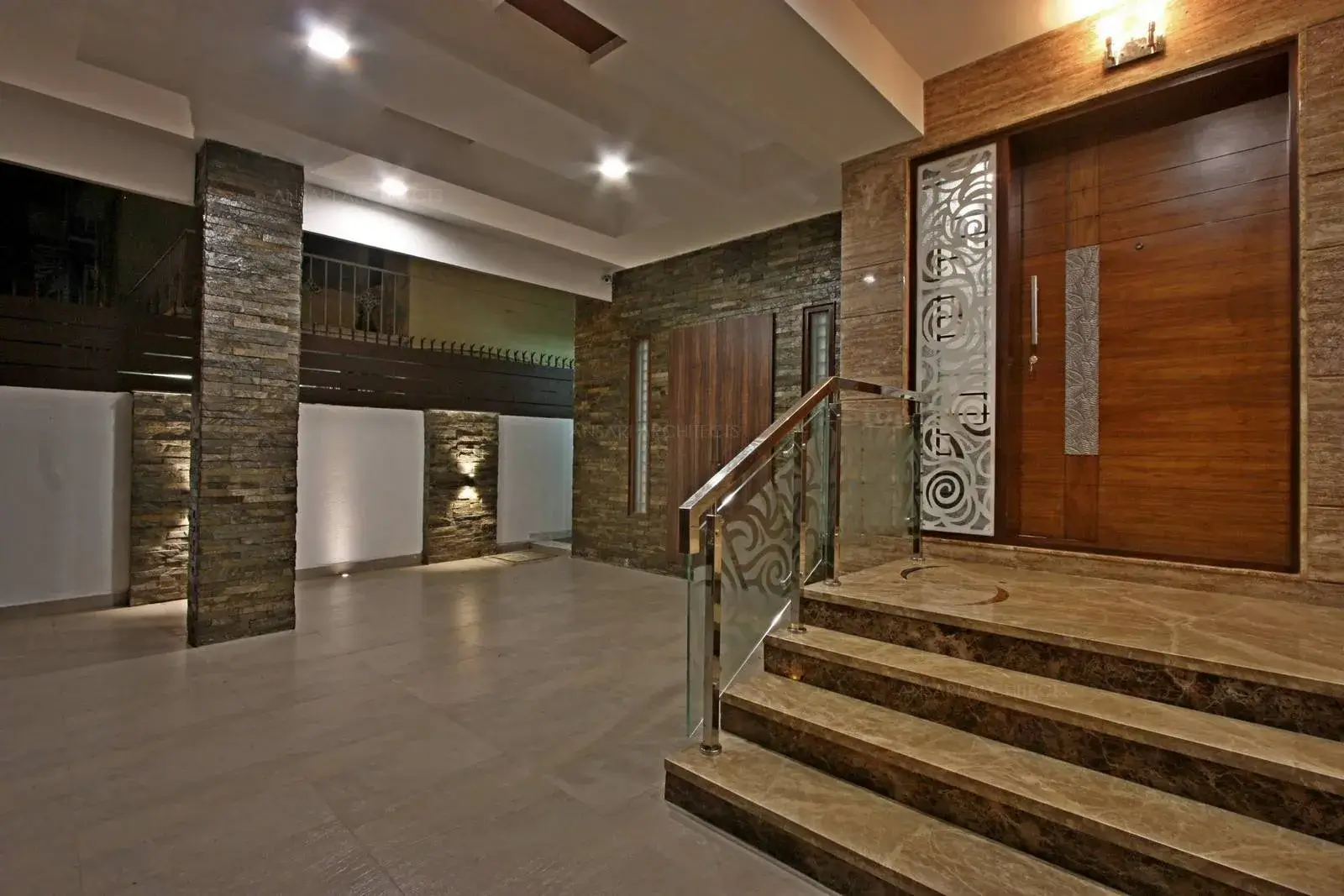 The Main door is embossed with different textures and usage of wood all around creates a warm look, lighting is used to highlight the texture effect.
