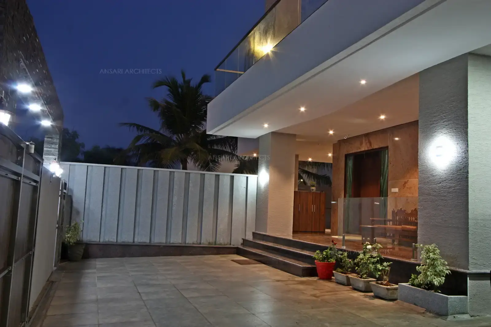 The car porch with lights, contemporary lanterns and a few glimpses of greenery, the flooring with natural stone tiles looks rustic adds texture and colour.