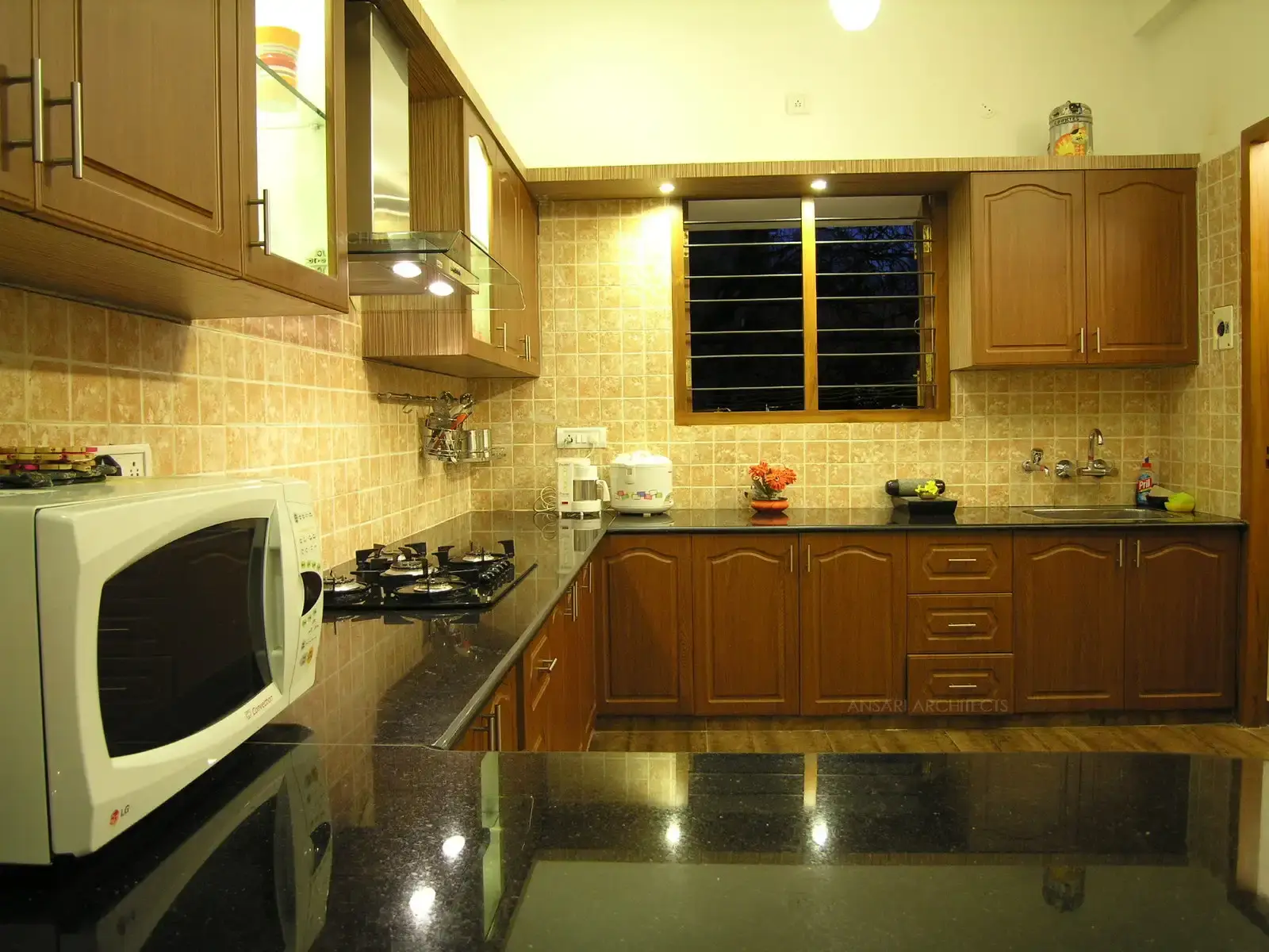 Kitchen has been designed in simple wooden cabinets with neutral wall and floor tiles.