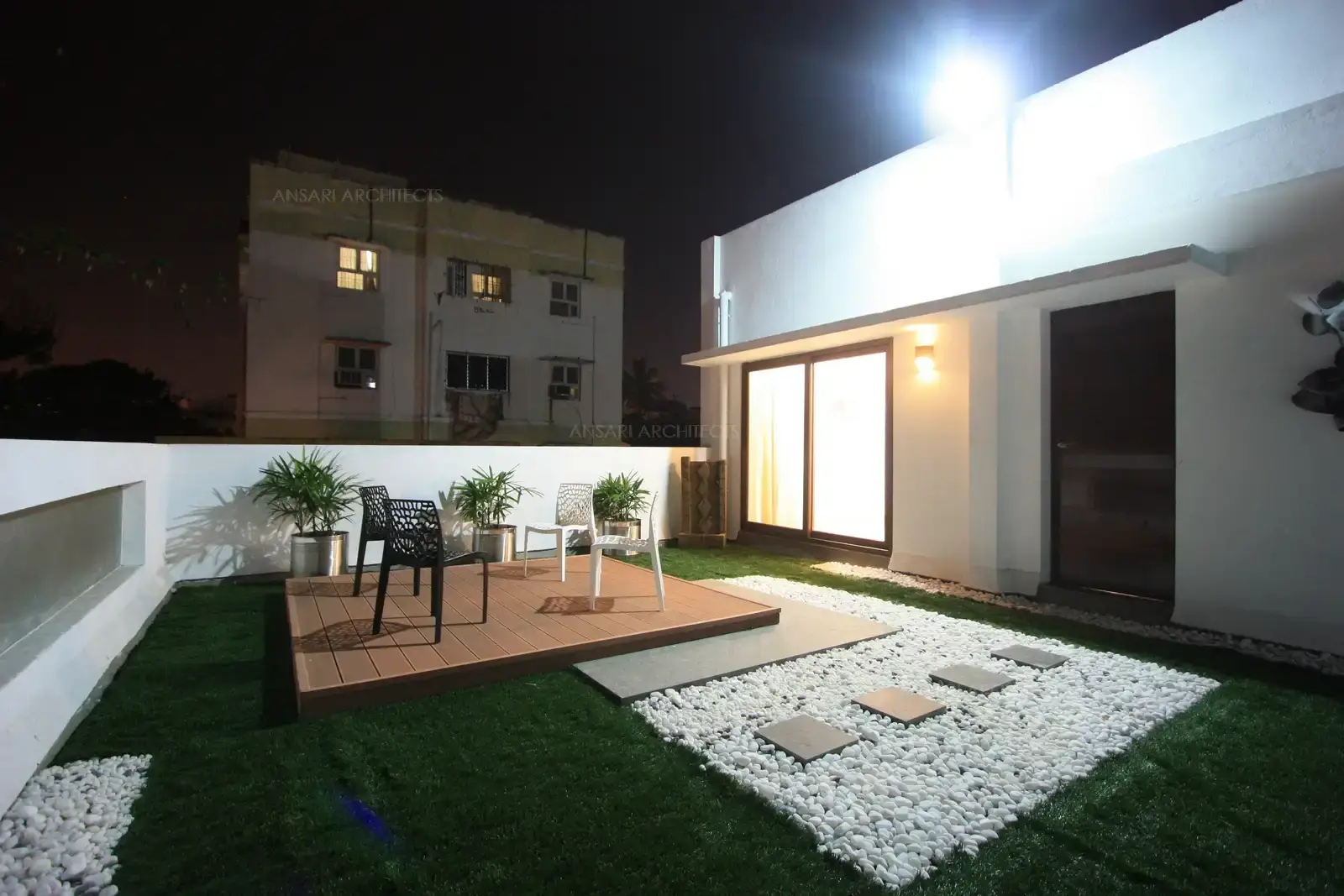 The terrace garden on the south side has been planned with raised wooden platform surrounding artificial grass turf with pebble flooring.