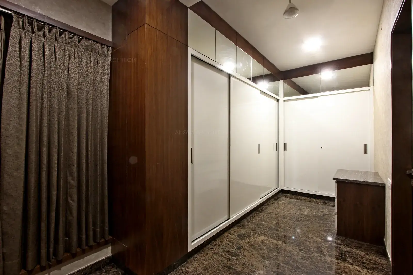 Dresser area with built-in wardrobes, the distressed finish dresser adds touch of warmth and earthiness to the neutral toned dresser also adds a subtle dose of style to the space and thereby connects two spaces.